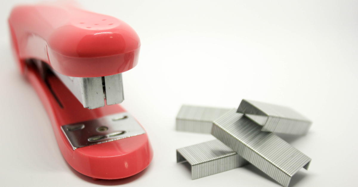 Red stapler next to a pile of staples.