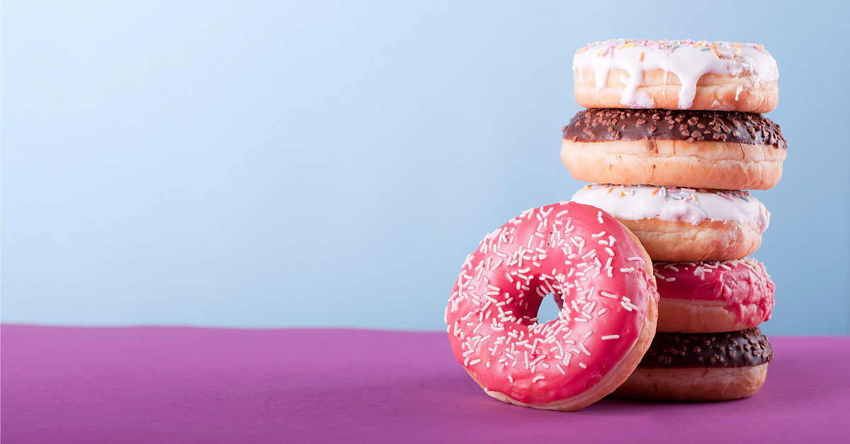 A stack of donuts on a fuschia-colored table.