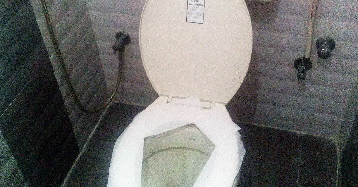 Toilet with the seat covered by toilet paper