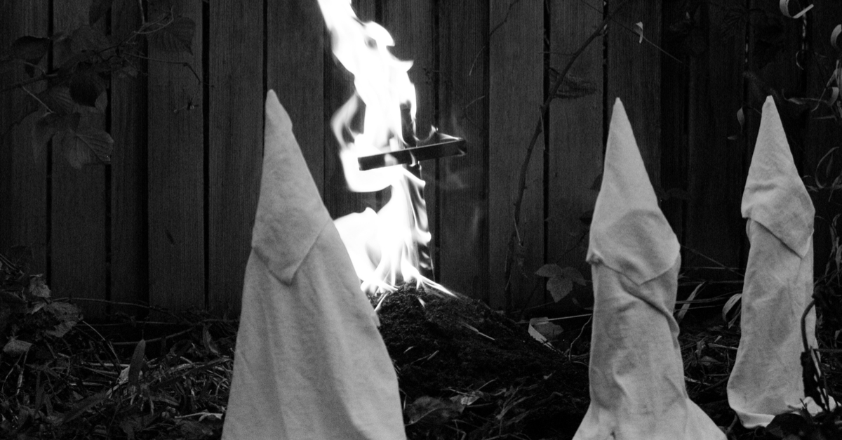 Ku Klux Klan in costumes burning a cross