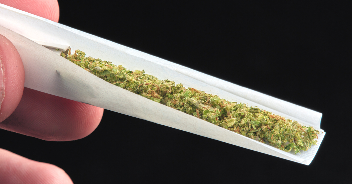 Hand holding a half-rolled joint