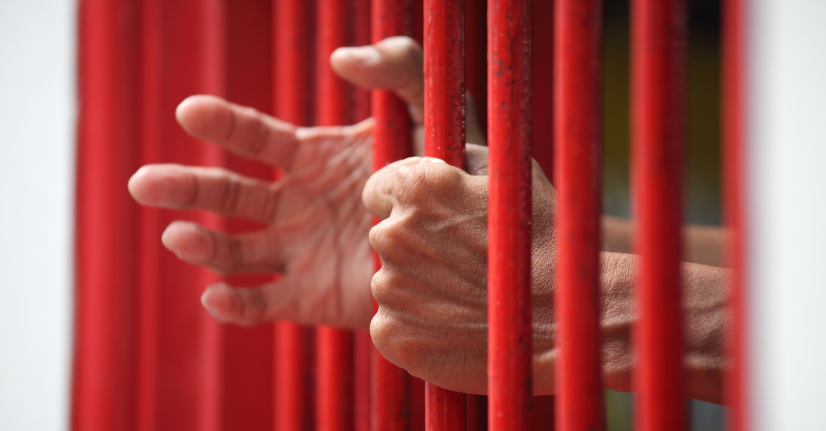 Hands reaching through cell bars