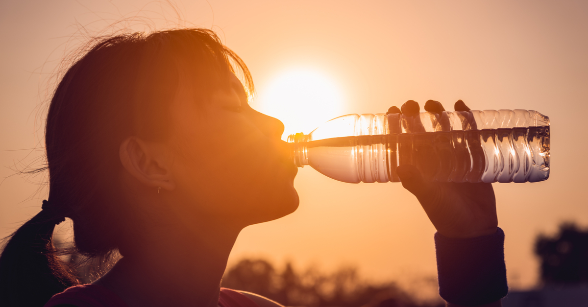 Silhouette of woman drinking a bottle of water.