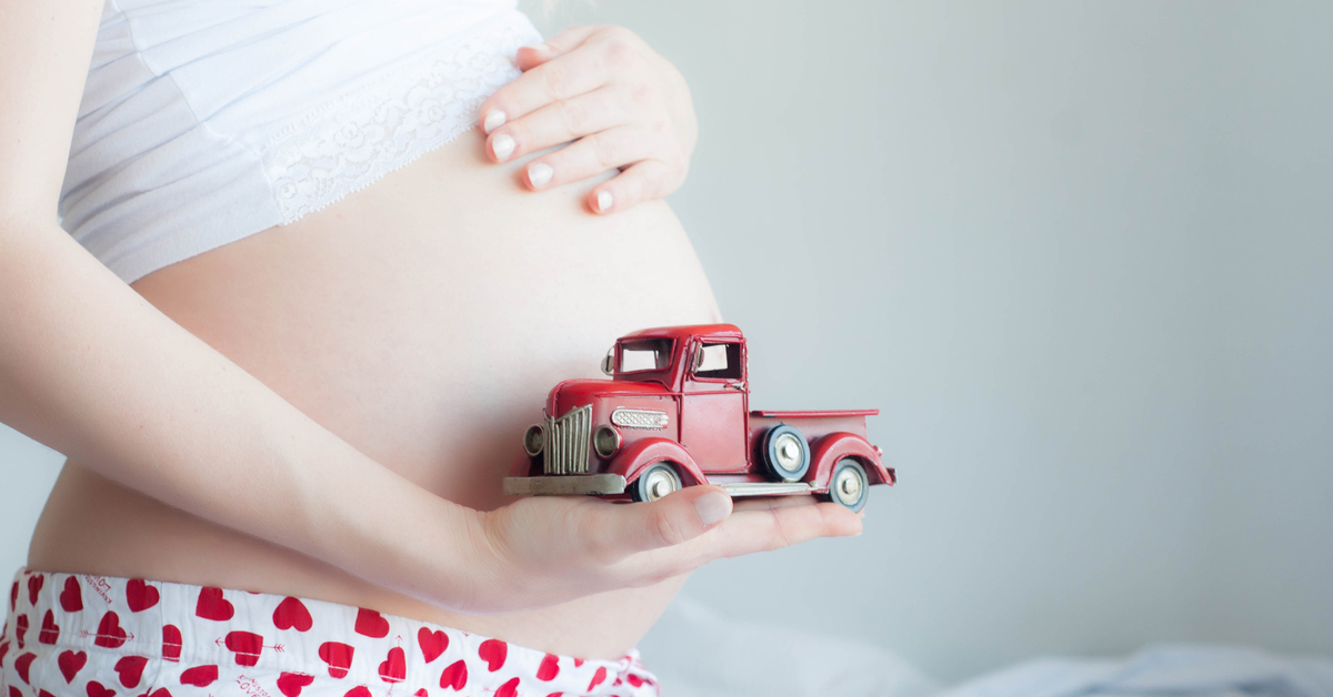 Pregnant woman holding toy truck next to her waist