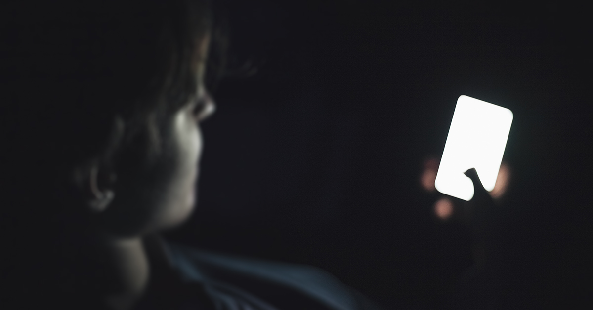Blurred teenage boy using cell phone in the dark