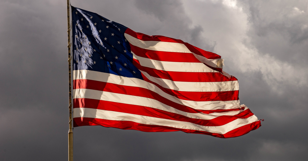 American flag against a gray, cloudy sky.
