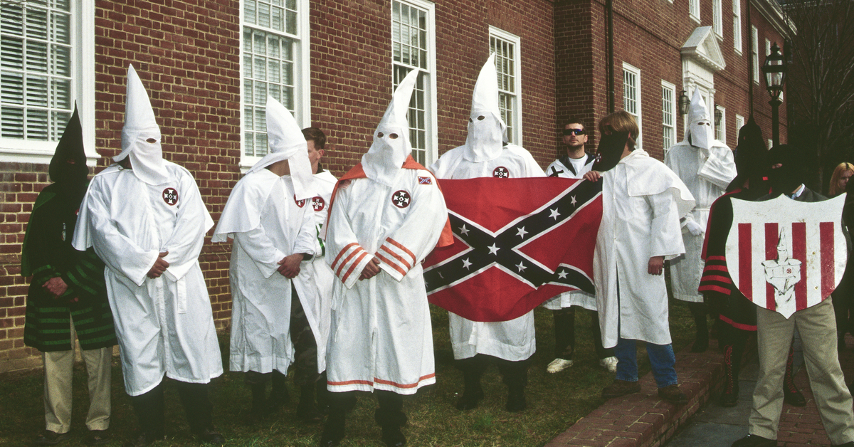 Klan members holding a Confederate flag.