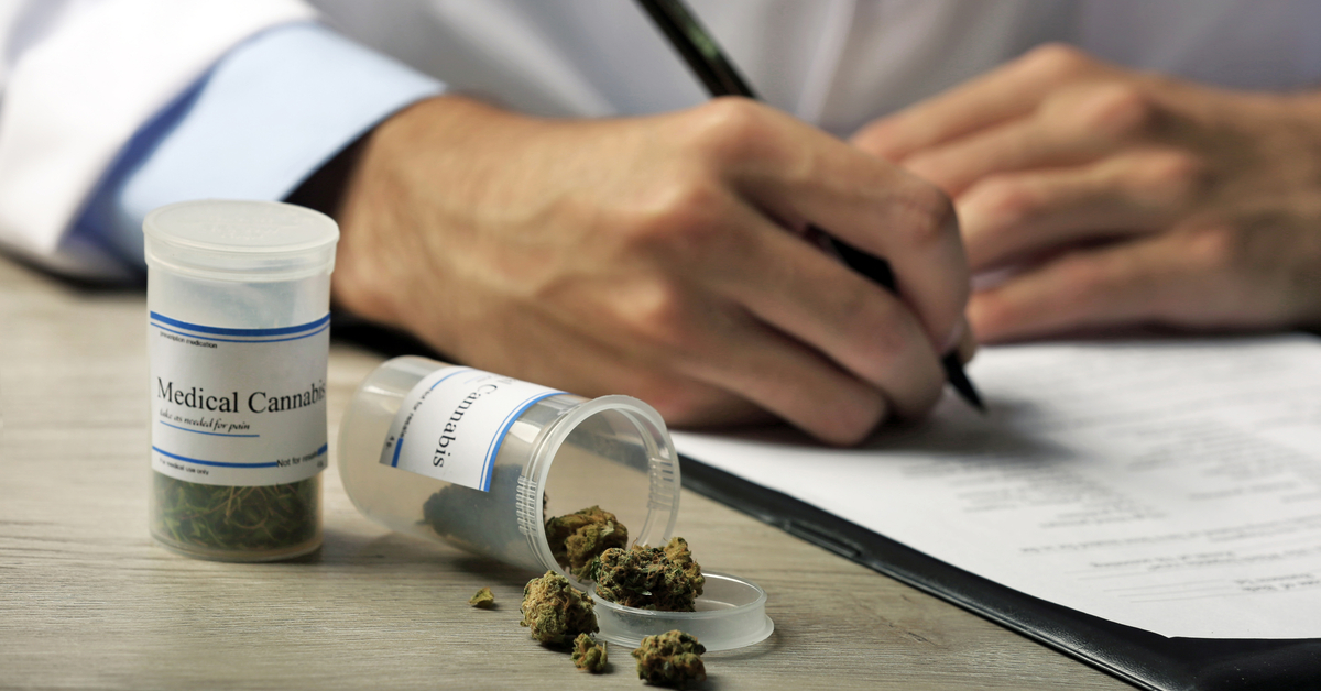 Doctor writing a prescription on a prescription pad with an open container of marijuana buds.