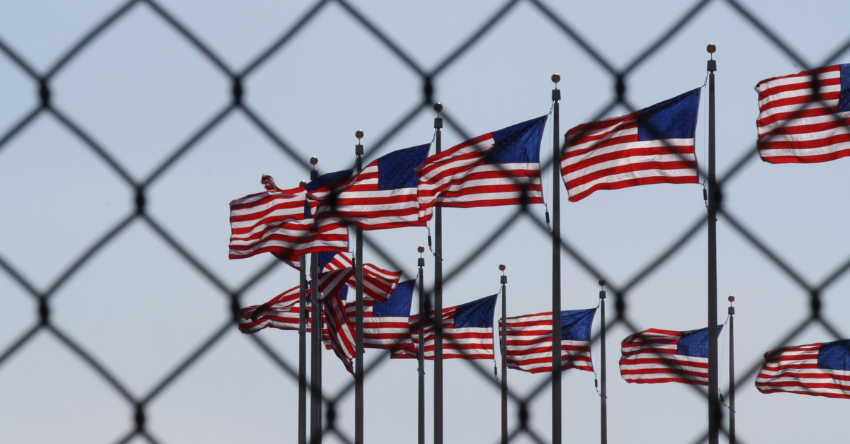 American flags as seen through a chainlink fence.
