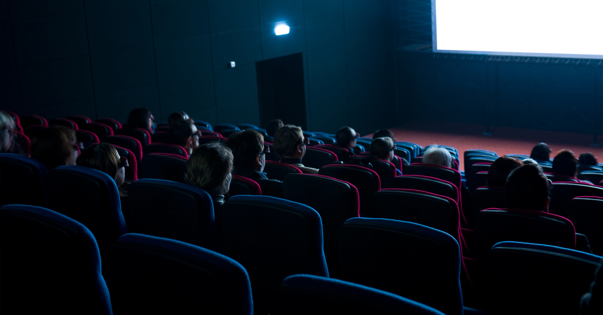People watching a film in a darkened movie theater.