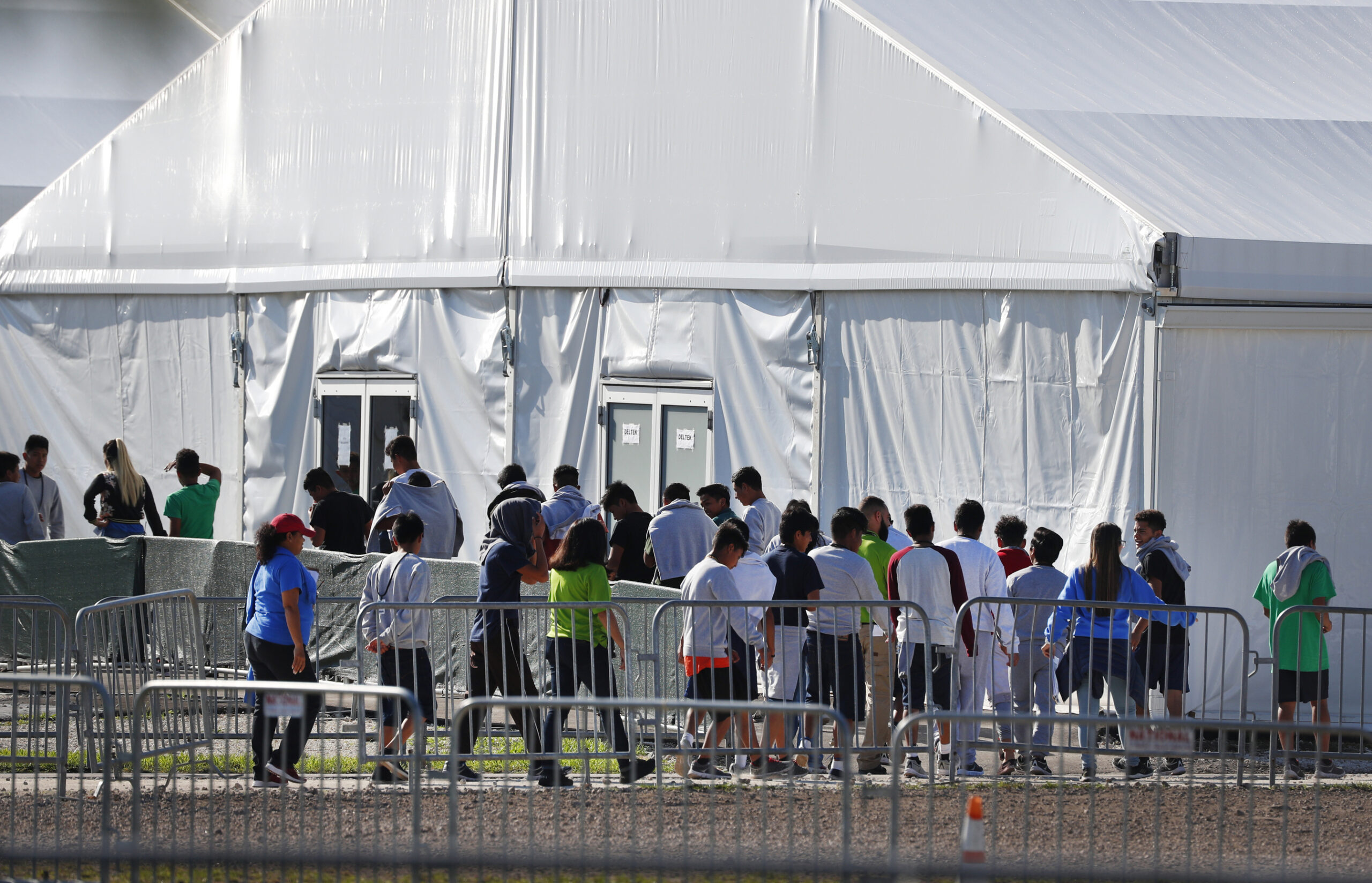FILE- In this Feb. 19, 2019, file photo, children line up to enter a tent at the Homestead Temporary Shelter for Unaccompanied Children in Homestead, Fla. Despite efforts by the Trump administration to improve communication to track children who are separated from their families at the border, the process is still vulnerable to error and information sharing between agencies is inconsistent, raising questions on the accuracy of current data, a watchdog reported Thursday. (AP Photo/Wilfredo Lee, File)
