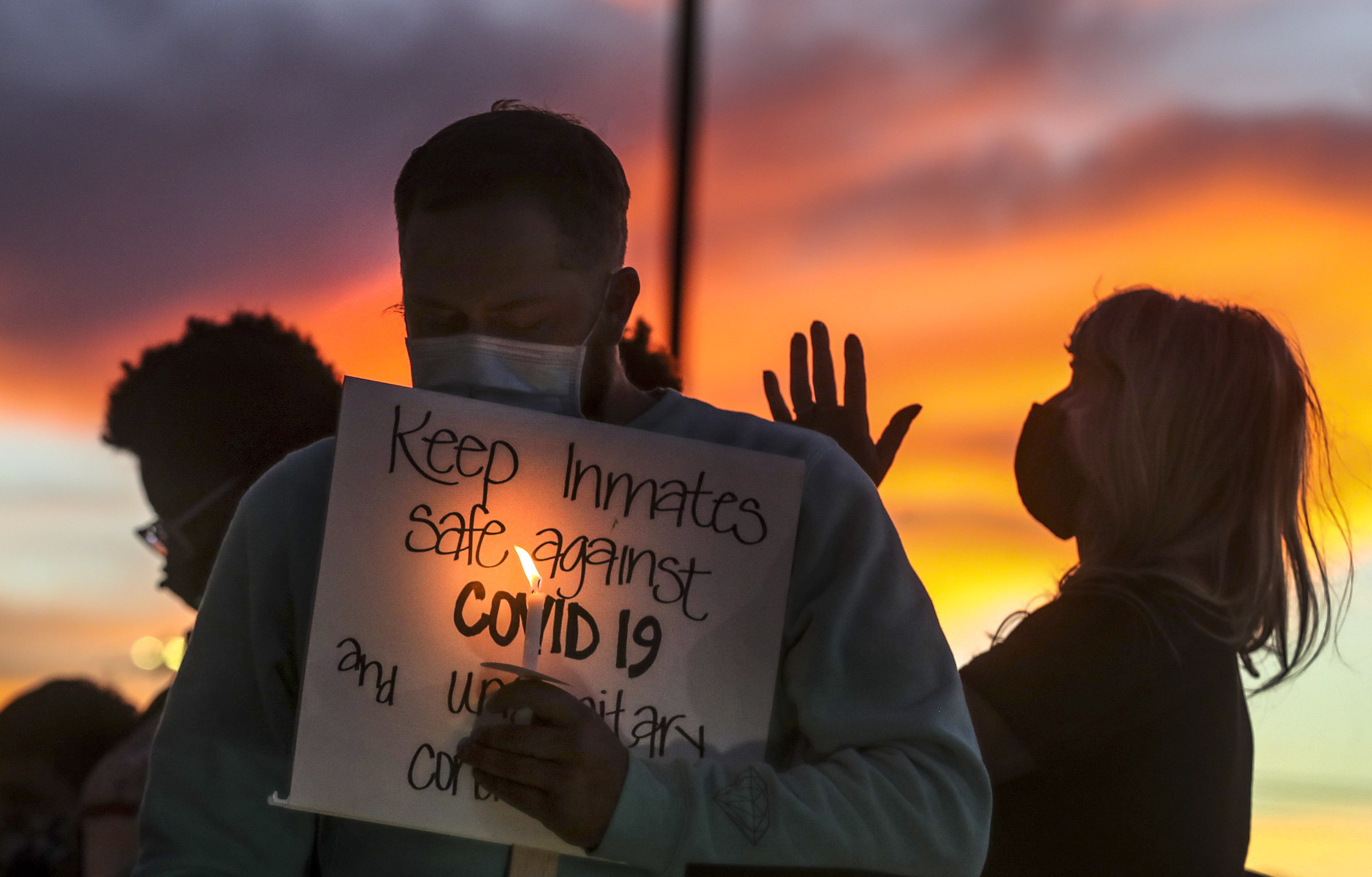FILE - In this Oct. 13, 2020, file photo, family members of inmates incarcerated in the Utah Department of Corrections' prison system hold candles and say a prayer following a rally outside the Department of Corrections office in Draper, Utah. One in five state and federal prisoners in the United States has tested positive for the coronavirus, a rate more than four times higher than the general population. In some states, more than half of prisoners have been infected, according to data collected by The Associated Press and The Marshall Project. (Steve Griffin/The Deseret News via AP, File)
