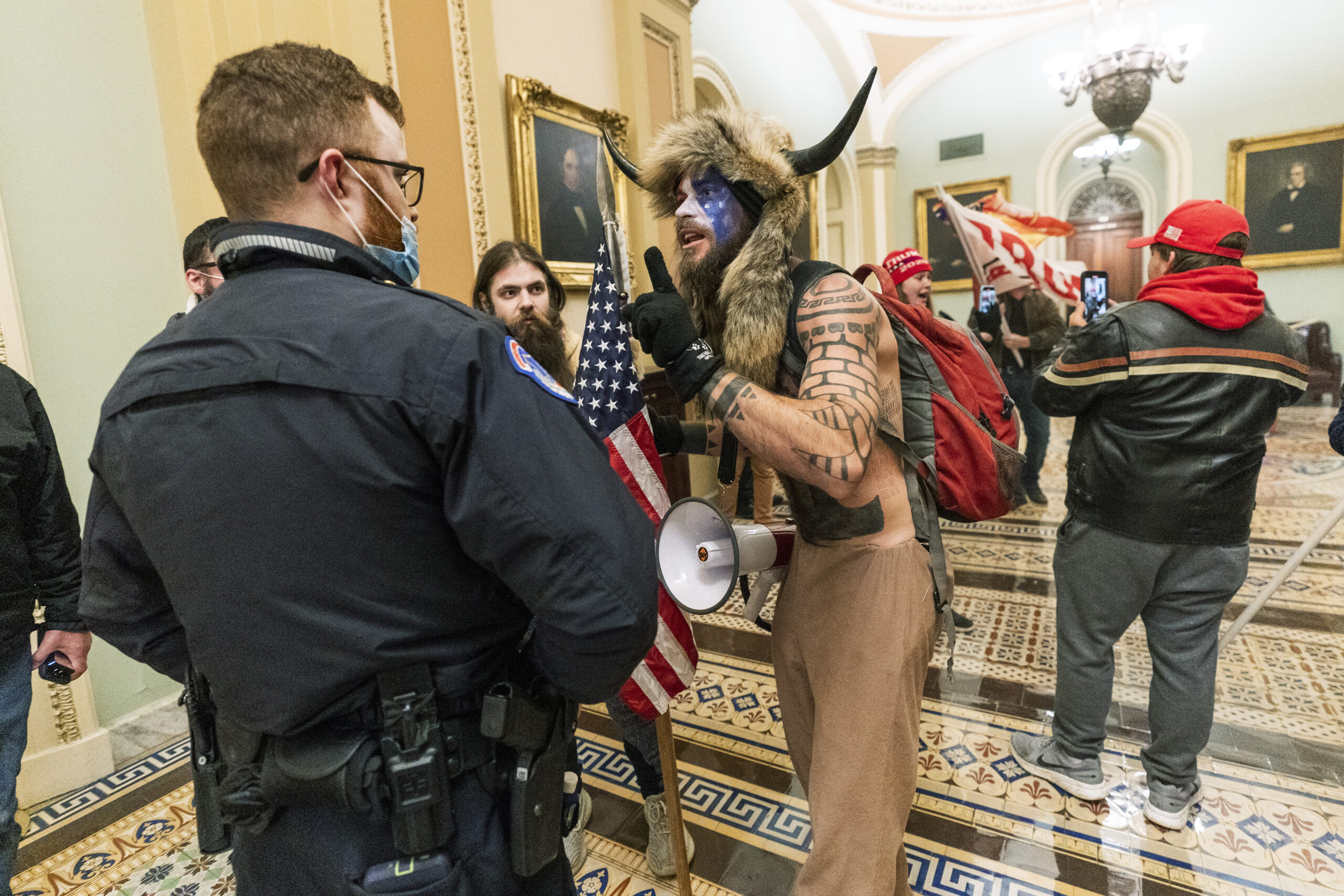 FILE - In this Jan. 6, 2021, file photo supporters of President Donald Trump are confronted by U.S. Capitol Police officers outside the Senate Chamber inside the Capitol in Washington. An Arizona man seen in photos and video of the mob wearing a fur hat with horns was also charged Saturday in Wednesday's chaos. Jacob Anthony Chansley, who also goes by the name Jake Angeli, was taken into custody Saturday, Jan. 9. (AP Photo/Manuel Balce Ceneta, File)