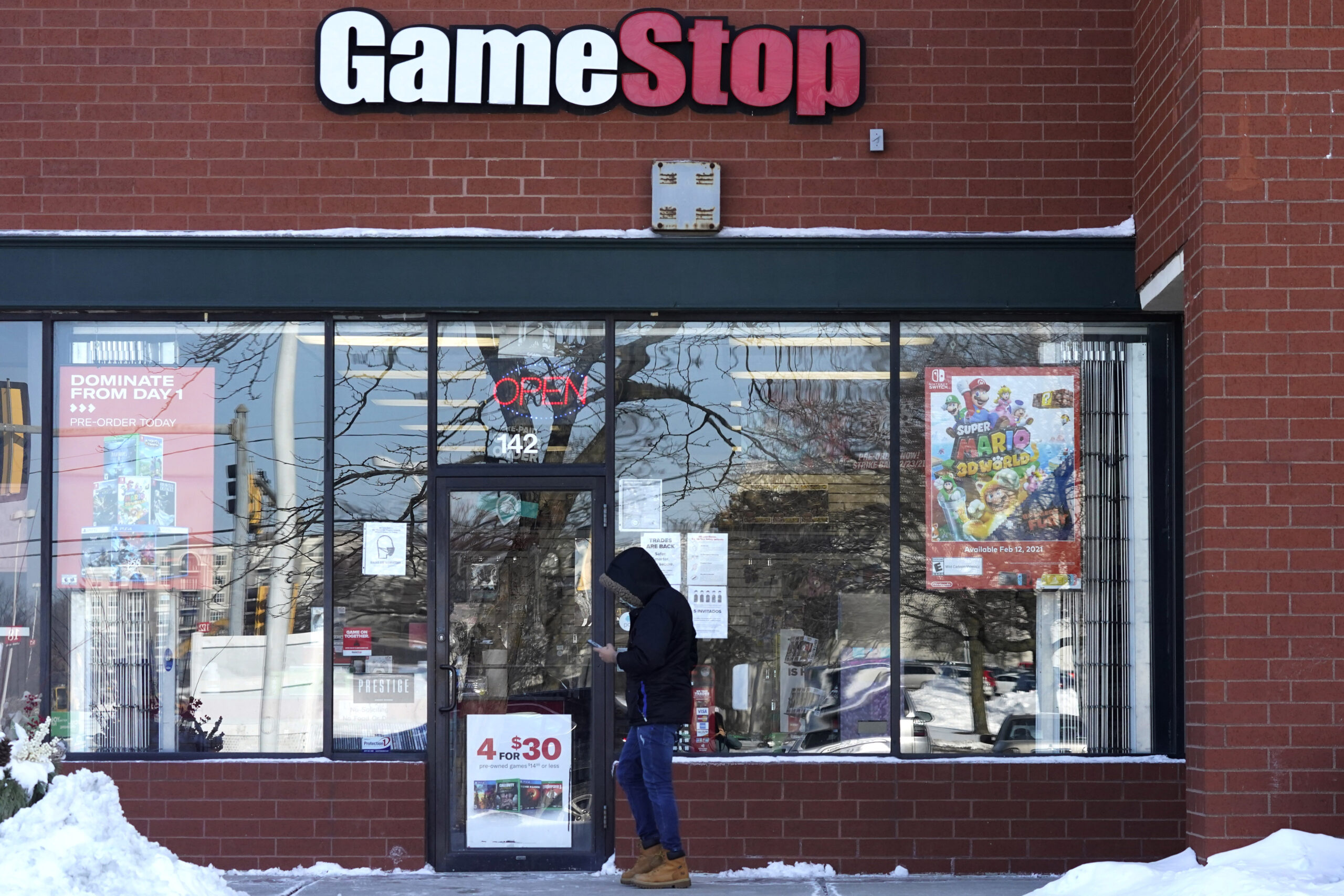 FILE - In this Jan. 28, 2021 file photo, a customer checks on his cellphone as he walks to a GameStop store in Vernon Hills, Ill. The frenzy around GameStop’s stock may have quieted down, but the outsized influence small investors had in the saga is likely to stick around. While no one expects another supernova like GameStop, the tools that smaller investors employed to supercharge its stock can be used again and again. (AP Photo/Nam Y. Huh, File)