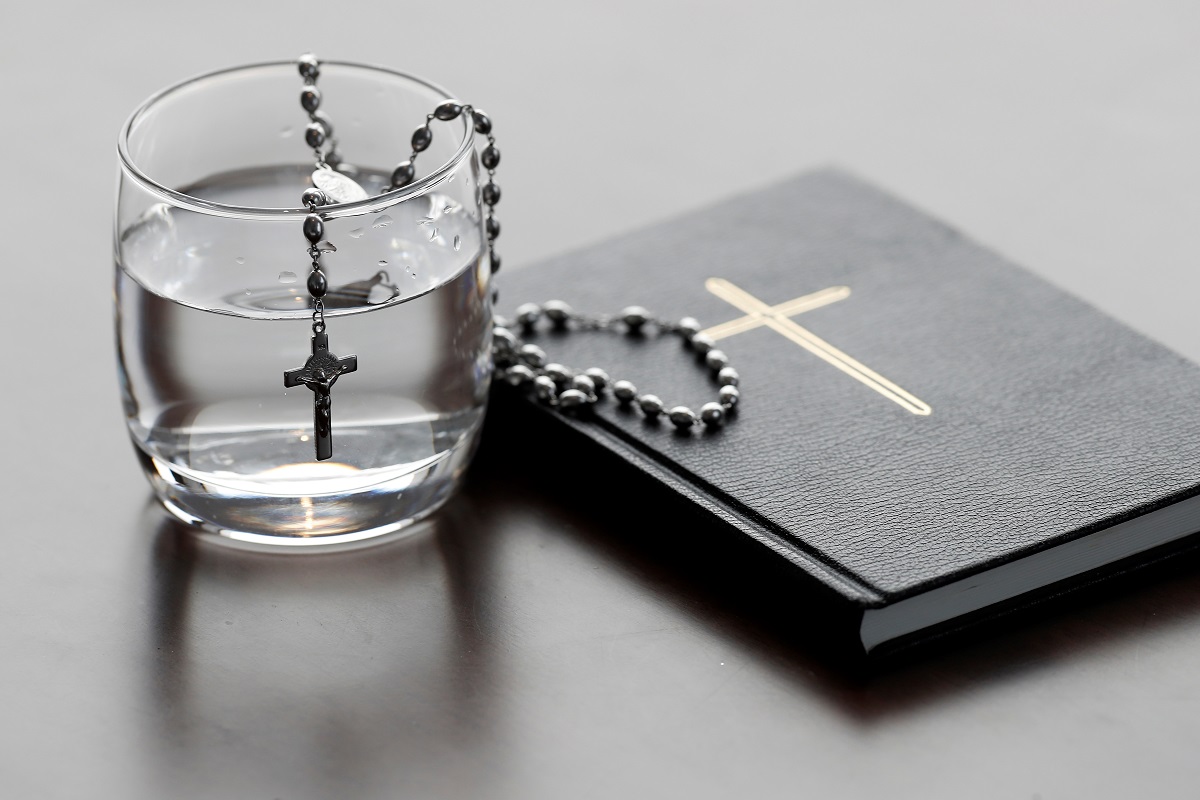 Rosary, glass of water, and holy Bible during Lent