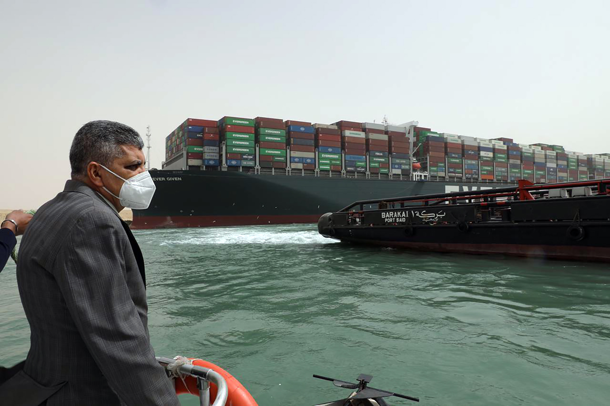 This photo released by the Suez Canal Authority on Thursday, March 25, 2021, shows Lt. Gen. Ossama Rabei, head of the Suez Canal Authority, investigating the situation with the Ever Given, a Panama-flagged cargo ship, after it become wedged across the Suez Canal and blocking traffic in the vital waterway. An operation is underway to try to work free the ship, which further imperiled global shipping Thursday as at least 150 other vessels needing to pass through the crucial waterway idled waiting for the obstruction to clear. (Suez Canal Authority via AP)
