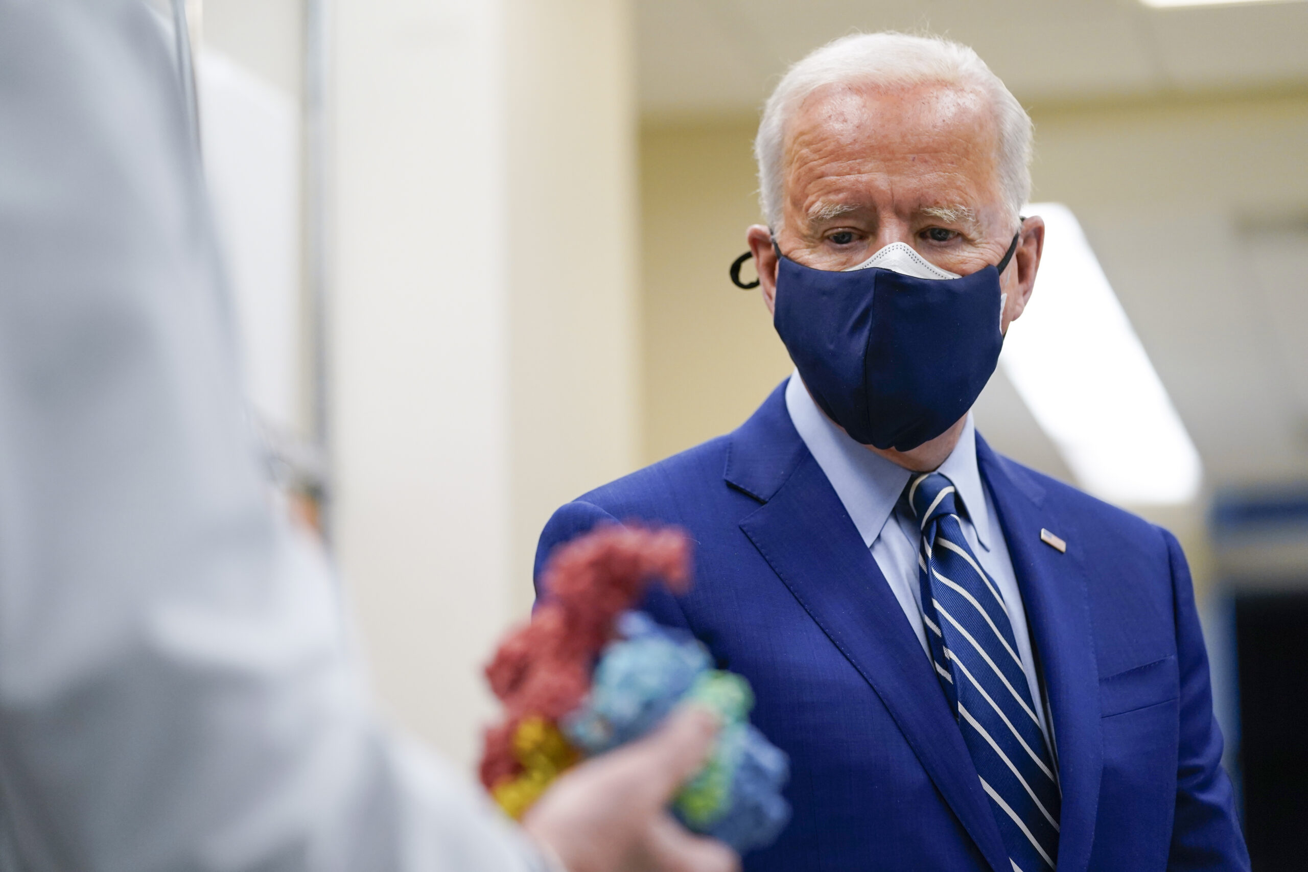 FILE - In this Feb. 11, 2021, file photo President Joe Biden looks at a model of Covid-19 as he visits the Viral Pathogenesis Laboratory at the National Institutes of Health in Bethesda, Md. (AP Photo/Evan Vucci, File)