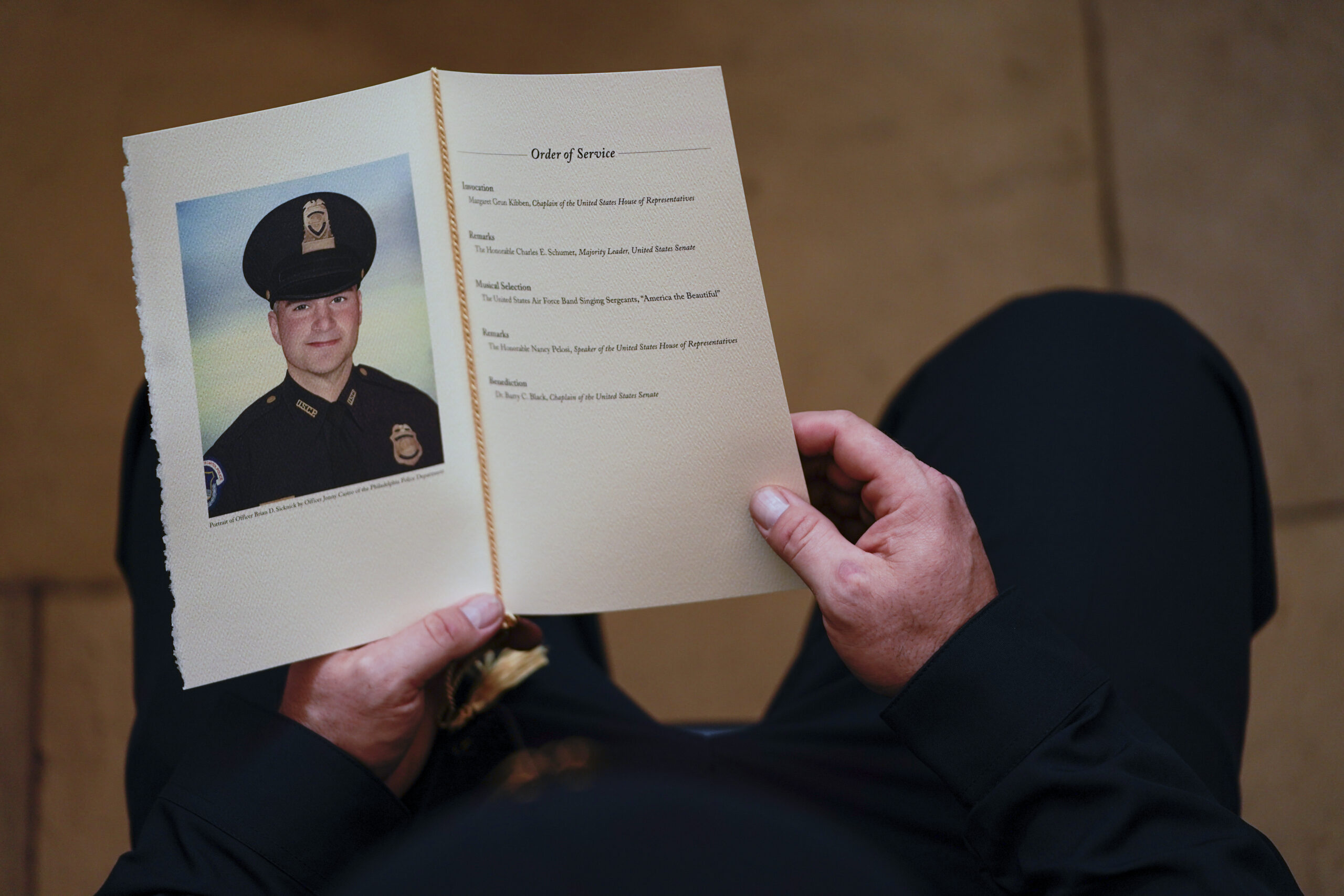 FILE - In this Feb. 3, 2021, file photo, a U.S. Capitol Police officer holds a program during a ceremony memorializing U.S. Capitol Police officer Brian Sicknick, as an urn with his cremated remains lies in honor on a black-draped table at the center of the Capitol Rotunda in Washington. The D.C. medical examiner’s office says Sicknick, who was injured during the Jan. 6 insurrection, suffered a stroke and ruled the officer died from natural causes. (Demetrius Freeman/The Washington Post via AP, Pool)