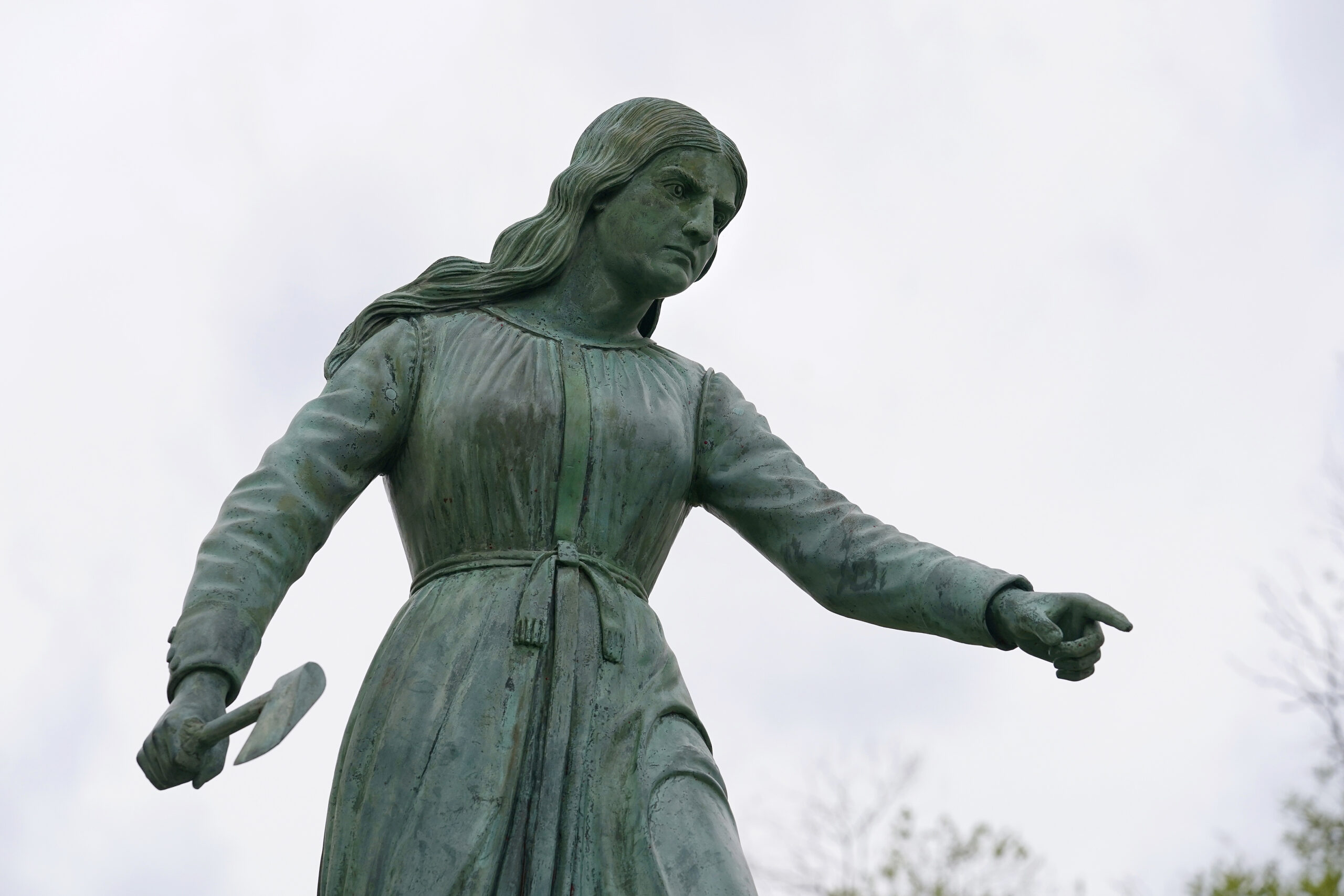 A statue of Hannah Duston, dated 1879, stands in the Grand Army of the Republic Park, Wednesday, April 28, 2021, in Haverhill, Mass., meant to honor the English colonist who, legend has it, slaughtered her Native American captors after the gruesome killing of her baby. But the statue in Haverhill, and another of Duston in New Hampshire, are being reconsidered amid the nationwide reckoning on racism and controversial public monuments. (AP Photo/Steven Senne)