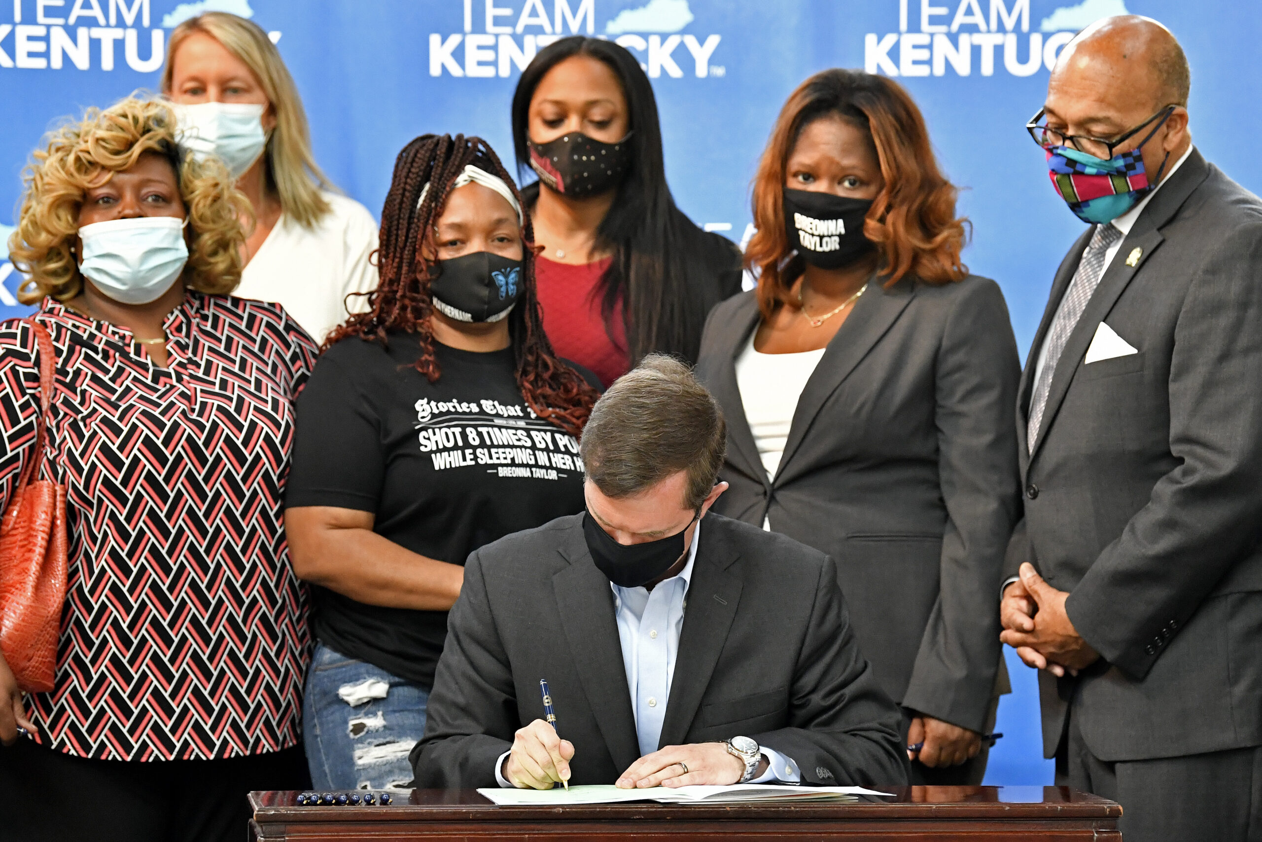Kentucky Gov. Andy Beshear signs a bill creating a partial ban on no-knock warrants, Friday, April 9, 2021, at the Center for African American Heritage Louisville, Ky. At the signing is Tamika Palmer, the mother of Breonna Taylor, behind Governor left. The bill signing comes after months of demonstrations set off by the fatal shooting of Taylor in her home during a botched police raid. (AP Photo/Timothy D. Easley)