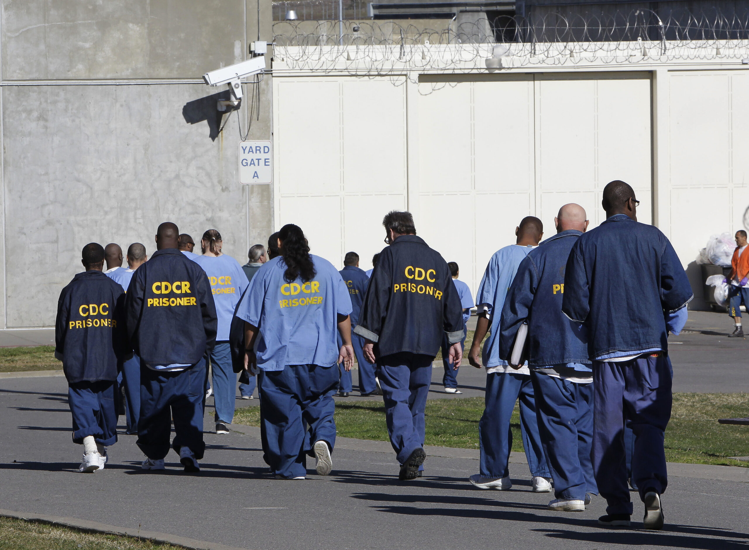 FILE - In this Feb. 26, 2013, file photo, inmates walk through the exercise yard at California State Prison Sacramento, near Folsom, Calif. California is giving 76,000 inmates, including violent and repeat felons, the opportunity to leave prison earlier as the state aims to further trim the population of what once was the nation's largest state correctional system. The new rules take effect Saturday, May 1, 2021, but it will be months or years before any inmates go free earlier. (AP Photo/Rich Pedroncelli, File)
