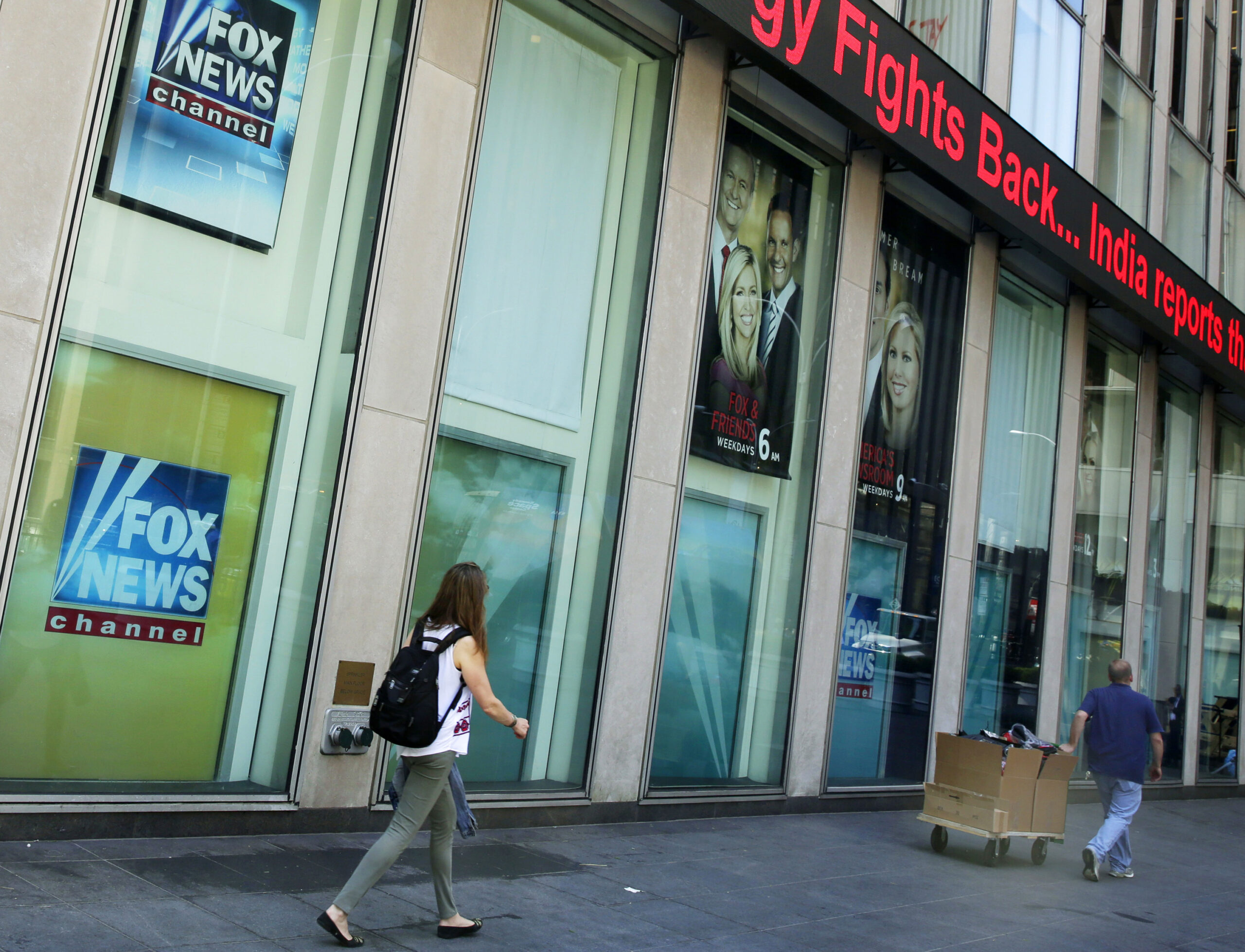 FILE- People pass the News Corporation headquarters building and Fox News studios in New York on Aug. 1, 2017. New York City's human rights commission has fined Fox News $1 million for violation of laws protecting against sexual harassment and job retaliation. It's the largest such penalty in the commission's history. (AP Photo/Richard Drew, File)