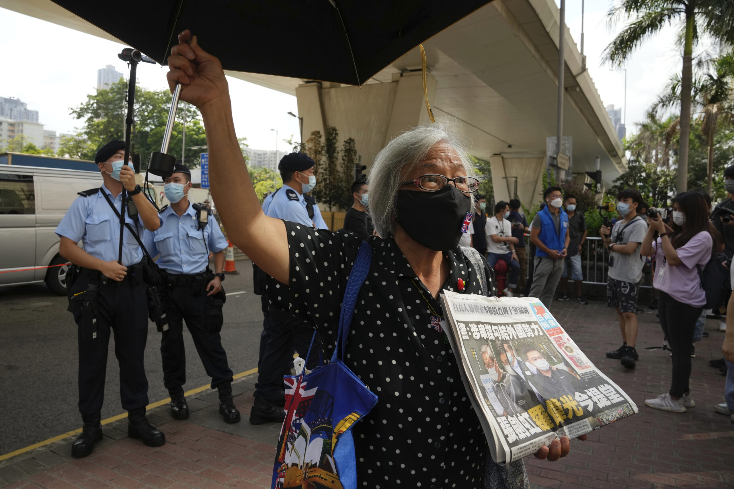 A pro-democracy activist holding a copy of Apple Daily newspaper protests outside a court in Hong Kong, Saturday, June 19, 2021, to demand to release political prisoners. The top editor of the Hong Kong's pro-democracy newspaper and the head of its parent company were brought to a courthouse Saturday for their first hearing since their arrest under the city's national security law.(AP Photo/Kin Cheung)