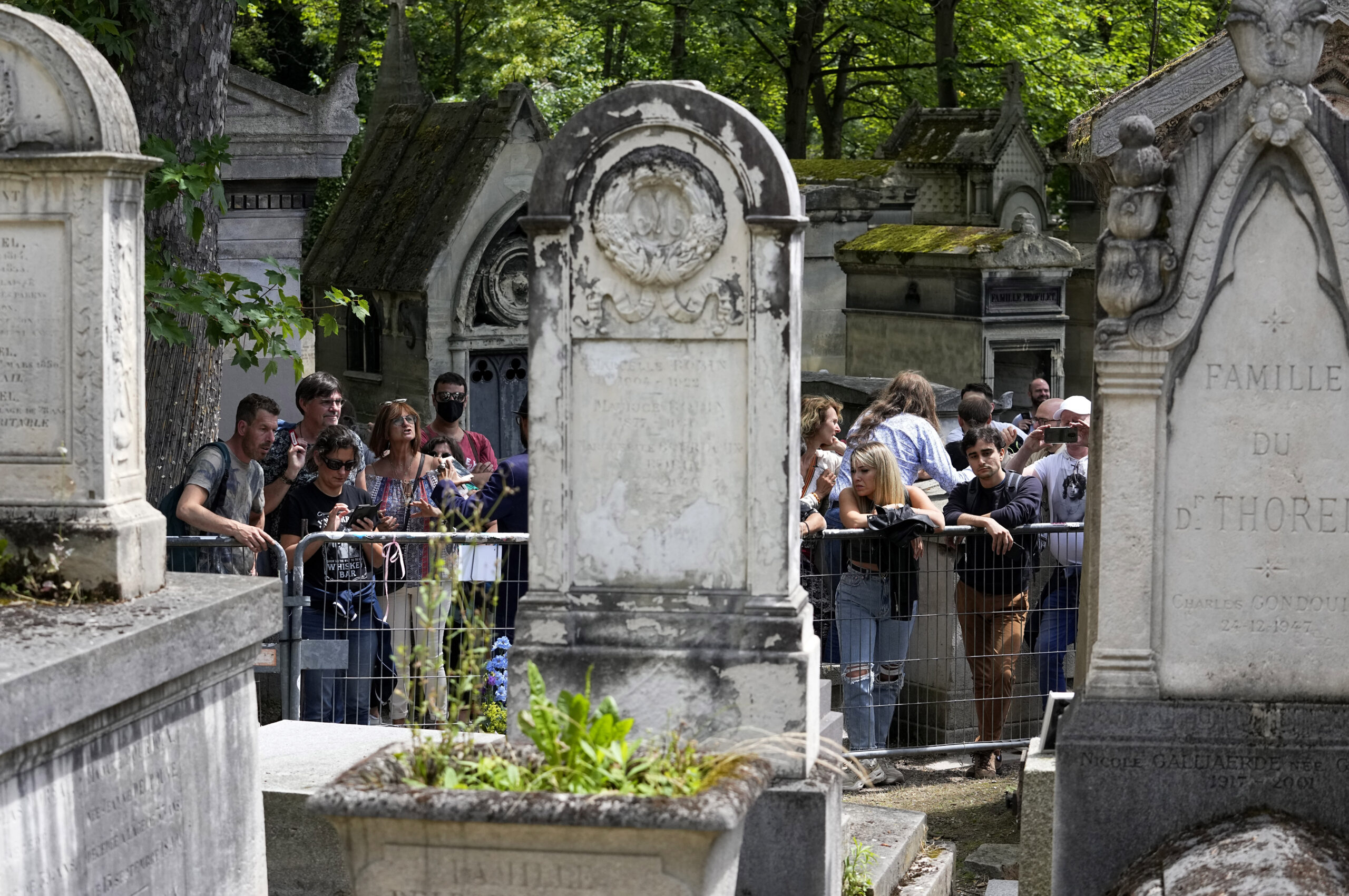Fans gather at the tomb of rock singer Jim Morrison at the Pere-Lachaise cemetery in Paris, Saturday, July 3, 2021. Fans across Europe gathered at the grave of rock legend Jim Morrison to mark the 50th anniversary of his death.(AP Photo/Michel Euler)