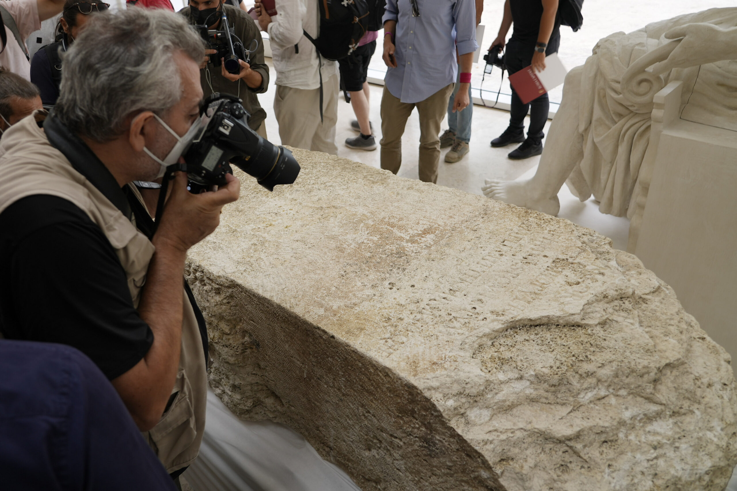 Photographers take pictures during the presentation to the press of an archeological finding emerged during the excavations at a Mausoleum in Rome, Friday, July 16, 2021. The monumental pomerial stone is dating back to Roman Emperor Claudio and was used to mark the ‘pomerium’ the sacred boundaries of the ‘Urbe’, the city of Rome, during the Roman empire. (AP Photo/Domenico Stinellis)
