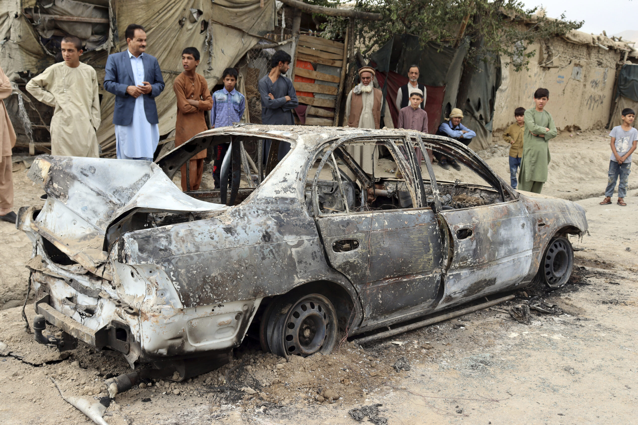 Locals view a vehicle damaged by a rocket attack in Kabul, Afghanistan, Monday, Aug. 30, 2021. Rockets struck a neighborhood near Kabul's international airport on Monday amid the ongoing U.S. withdrawal from Afghanistan. It wasn't immediately clear who launched them. (AP Photo/Khwaja Tawfiq Sediqi)