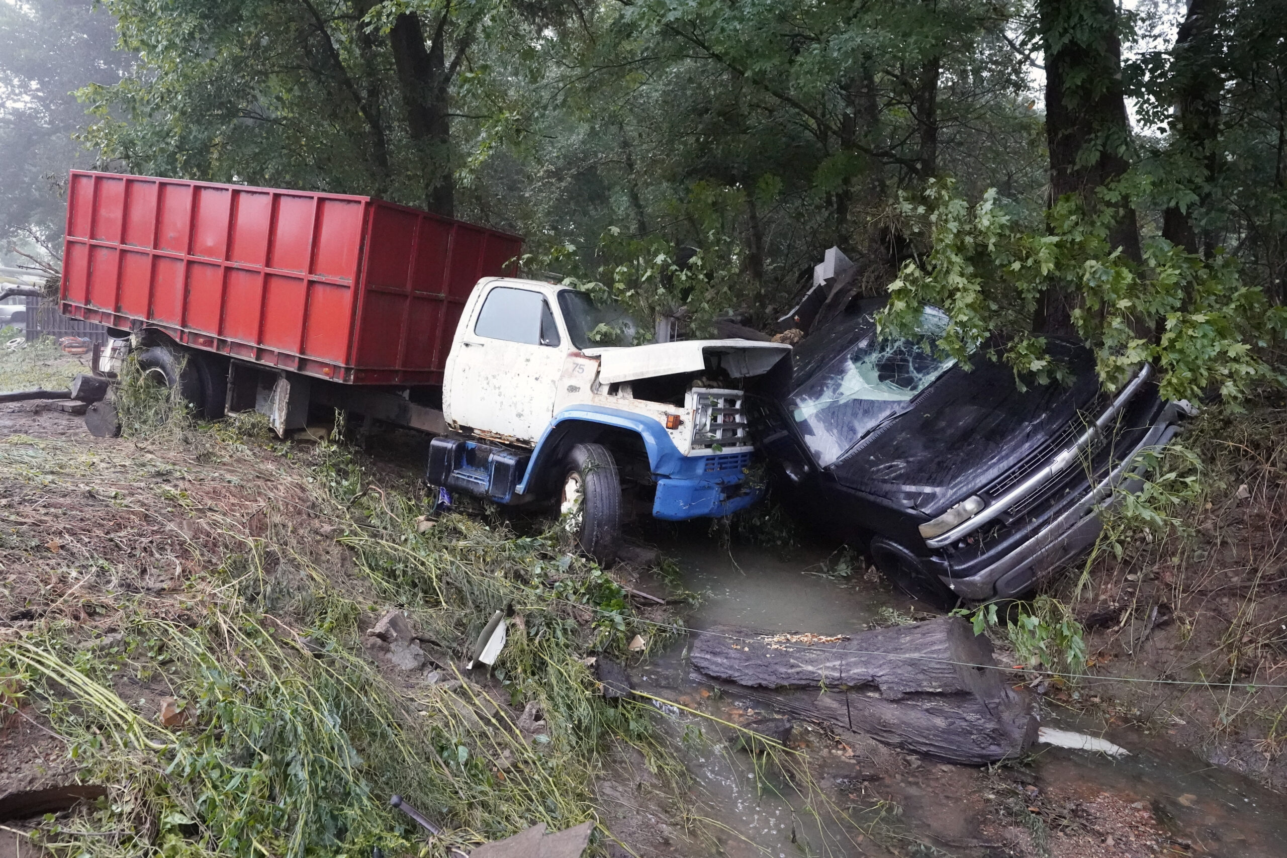 A truck and a car sit in a creek Sunday, Aug. 22, 2021, after they were washed away the day before in McEwen, Tenn. Heavy rains caused flooding in Middle Tennessee and have resulted in multiple deaths as homes and rural roads were washed away. (AP Photo/Mark Humphrey)