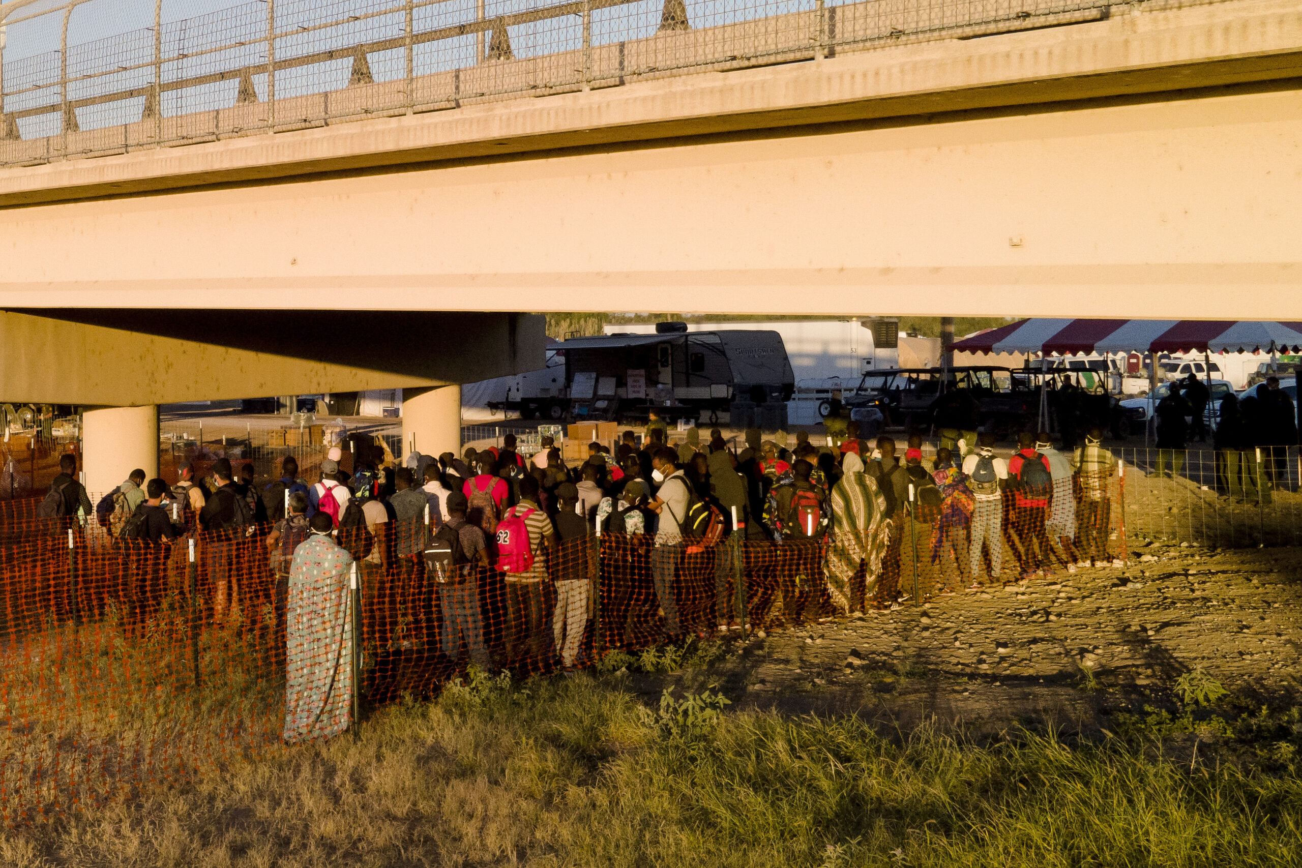 Migrants, many from Haiti, wait in lines to board buses under the Del Rio International Bridge, Friday, Sept. 24, 2021, in Del Rio, Texas. (AP Photo/Julio Cortez)