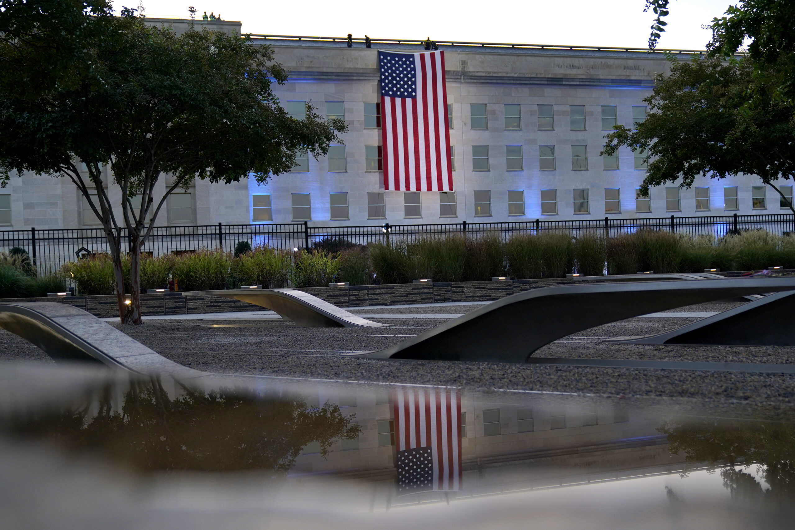 An American flag is unfurled at the Pentagon in Washington, Saturday, Sept. 11, 2021, at sunrise on the morning of the 20th anniversary of the terrorist attacks. The American flag is draped over the site of impact at the Pentagon. In the foreground, the National 9/11 Pentagon Memorial, opened in 2008 adjacent to the site, commemorates the lives lost at the Pentagon and onboard American Airlines Flight 77. (AP Photo/Alex Brandon)