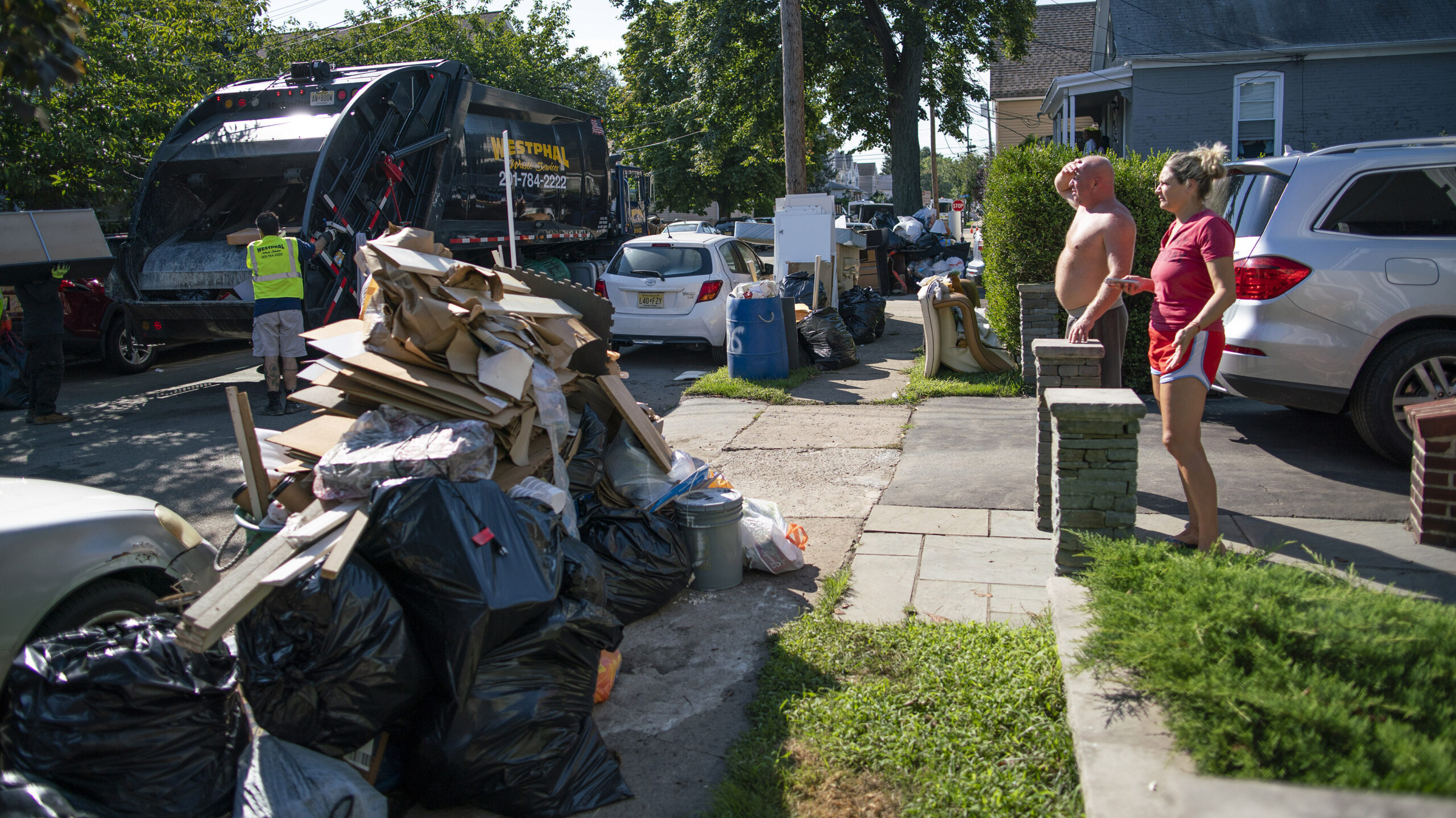 Residents wait a worker picking up debris, Monday, Sept. 6, 2021, in Passaic, NJ., from their flood damaged home in the aftermath of Hurricane Ida. (AP Photo/Eduardo Munoz Alvarez)