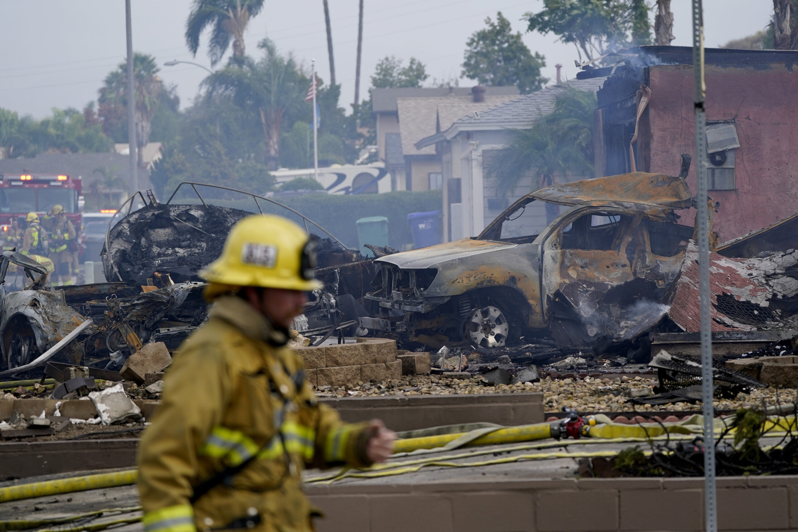 Fire crews work the scene of a small plane crash, Monday, Oct. 11, 2021, in Santee, Calif. At least two people were killed and two others were injured when the plane crashed into a suburban Southern California neighborhood, setting two homes ablaze, authorities said. (AP Photo/Gregory Bull)