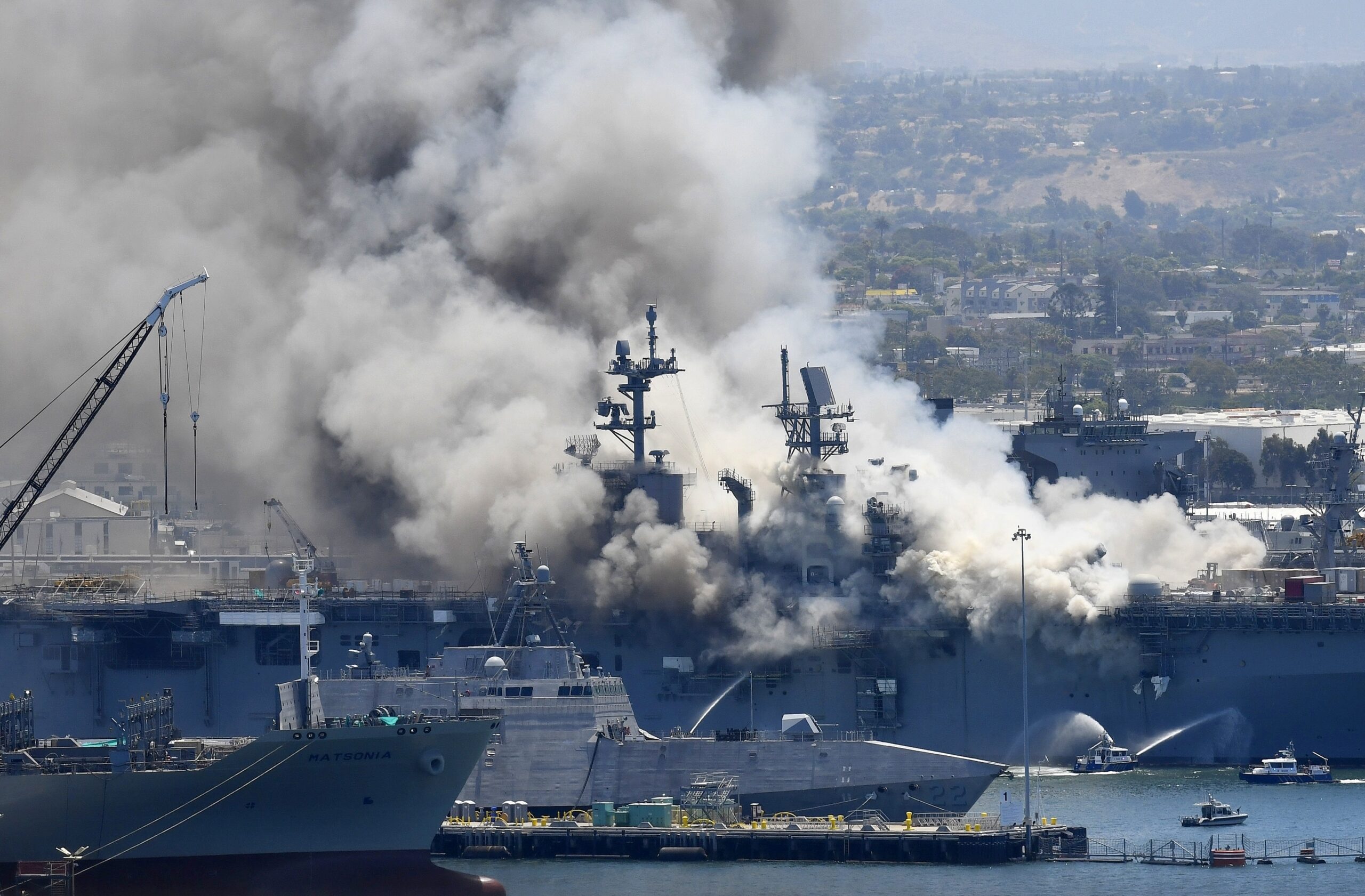 FILE - In this July 12, 2020, file photo, smoke rises from the USS Bonhomme Richard at Naval Base San Diego in San Diego, after an explosion and fire on board the ship at Naval Base San Diego. A Navy report has concluded there were sweeping failures by commanders, crew members and others that fueled the July 2020 arson fire that destroyed the USS Bonhomme Richard, calling the massive five-day blaze in San Diego preventable and unacceptable. While one sailor has been charged with setting the fire, the more than 400-page report, obtained by The Associated Press, lists three dozen officers and sailors whose failings either directly led to the ship's loss or contributed to it. (AP Photo/Denis Poroy, File)