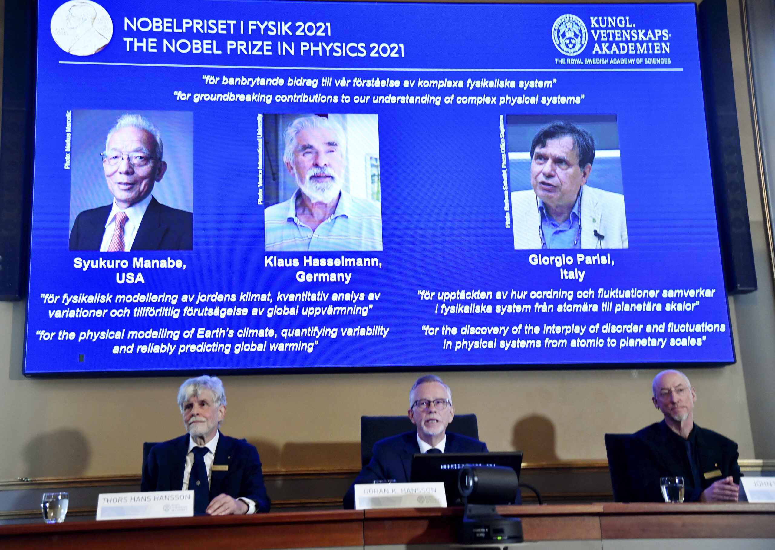 Secretary General of the Royal Swedish Academy of Sciences Goran Hansson, center, flanked at left by member of the Nobel Committee for Physics Thors Hans Hansson, left, and member of the Nobel Committee for Physics John Wettlaufer, right, announces the winners of the 2021 Nobel Prize in Physics at the Royal Swedish Academy of Sciences, in Stockholm, Sweden, Tuesday, Oct. 5, 2021. The Nobel Prize for physics has been awarded to scientists from Japan, Germany and Italy. Syukuro Manabe and Klaus Hasselmann were cited for their work in “the physical modeling of Earth’s climate, quantifying variability and reliably predicting global warming”. The second half of the prize was awarded to Giorgio Parisi for “the discovery of the interplay of disorder and fluctuations in physical systems from atomic to planetary scales.” (Pontus Lundahl/TT via AP)