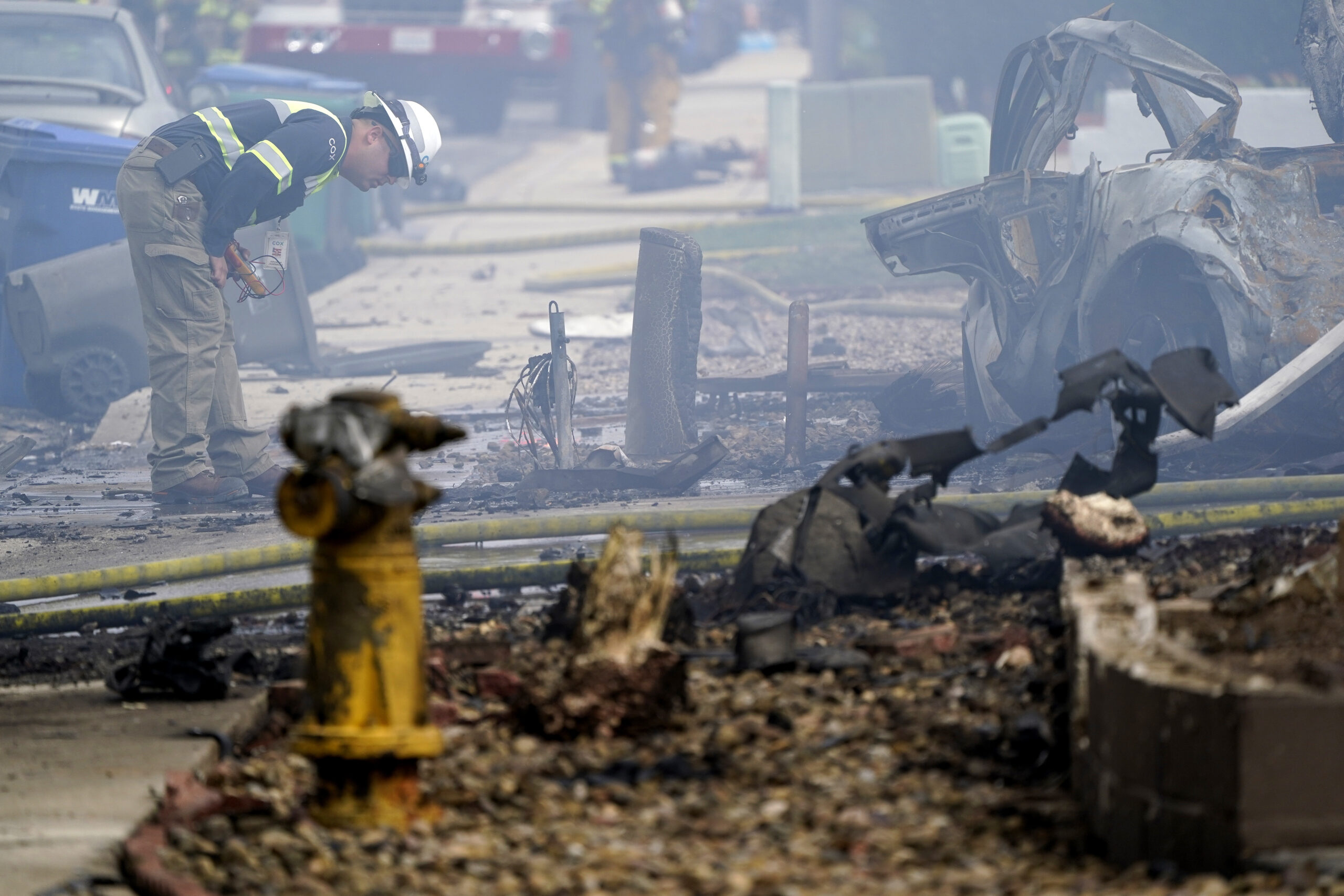 A fire official looks over the scene of a small plane crash, Monday, Oct. 11, 2021, in Santee, Calif. At least two people were killed and two others were injured when the plane crashed into a suburban Southern California neighborhood, setting two homes ablaze, authorities said. (AP Photo/Gregory Bull)