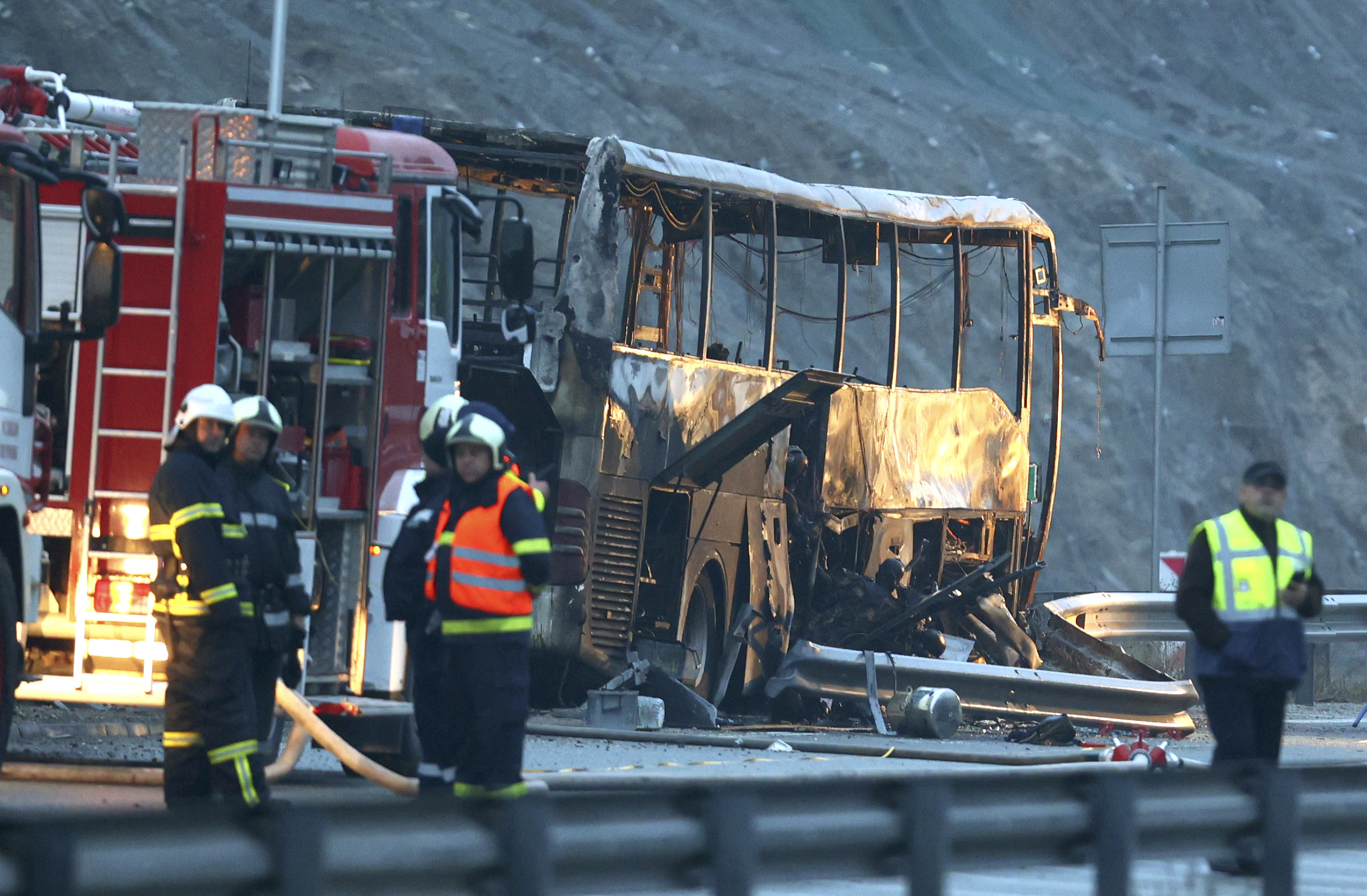 Firefighters and forensic workers inspect the scene of a bus crash which, according to authorities, killed at least 45 people on a highway near the village of Bosnek, western Bulgaria, Tuesday, Nov. 23, 2021. The bus, registered in Northern Macedonia, crashed around 2 a.m. and there were children among the victims, authorities said. (Minko Chernev/BTA Agency Bulgaria via AP)