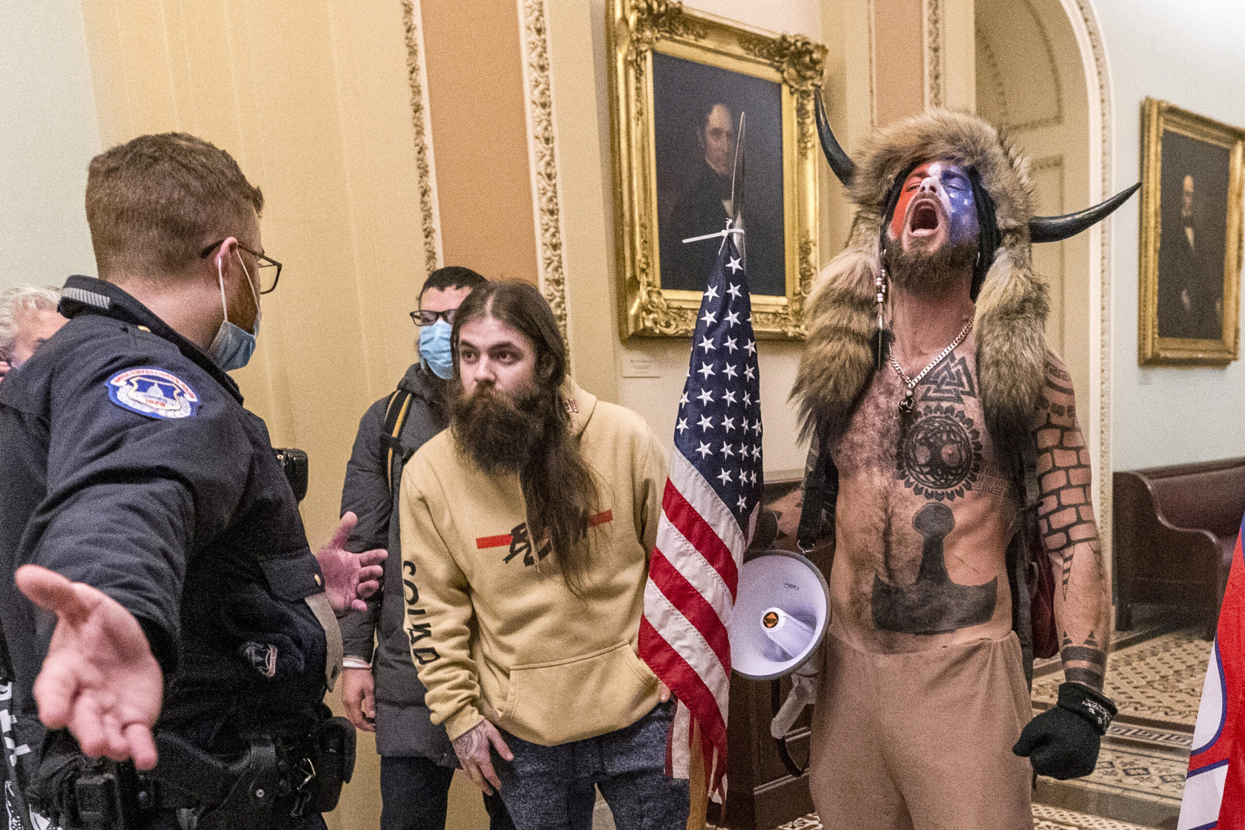 FILE - Supporters of President Donald Trump, including Jacob Chansley, right with fur hat, are confronted by U.S. Capitol Police officers outside the Senate chamber inside the Capitol during the capitol riot in Washington, Jan. 6, 2021. Chansley was sentenced on Wednesday, Nov. 17, 2021, to 41 months in prison for his felony conviction for obstructing an official proceeding. Though he wasn't accused of violence, Chansley acknowledged he was among the first 30 rioters in the building, offered thanks while in the Senate for having the chance to get rid of traitors and wrote a threatening note to Vice President Mike Pence. (AP Photo/Manuel Balce Ceneta, File)