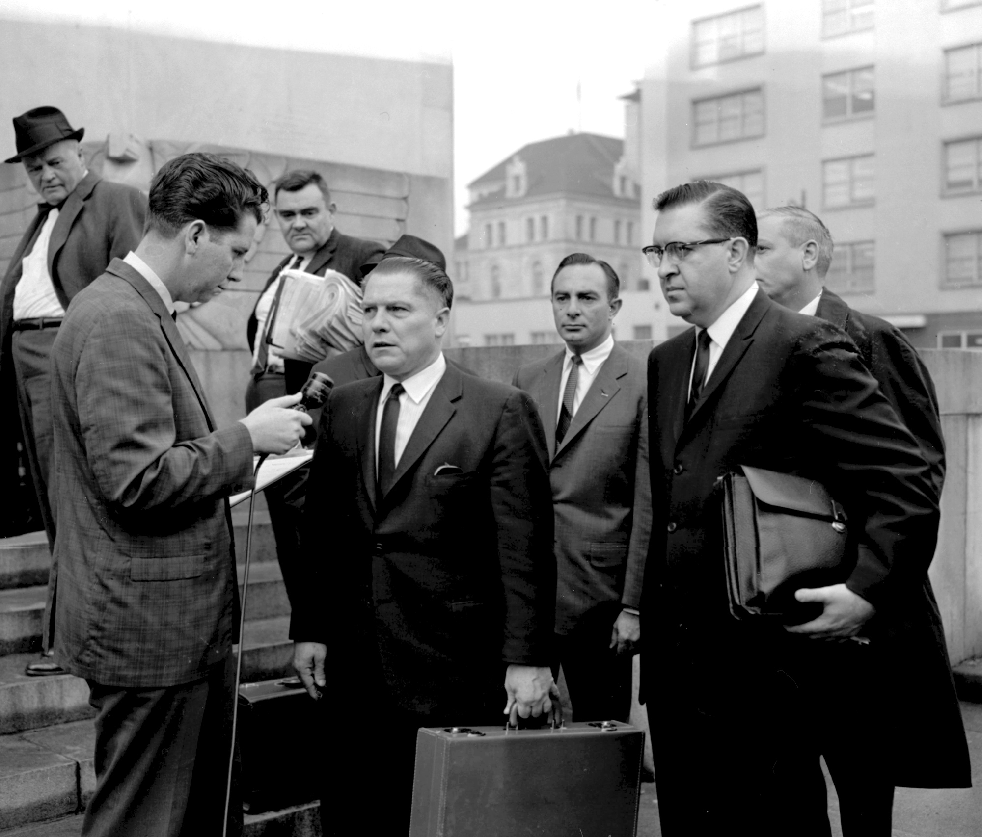 In this 1964 photo, a reporter questions Teamsters President Jimmy Hoffa outside the federal courthouse in Chattanooga, Tenn., during Hoffa's trial that ended in a jury tampering conviction. The decades-long odyssey to find the body of former Teamsters boss Jimmy Hoffa apparently has turned to a former New Jersey landfill below an elevated highway. The FBI obtained a search warrant to "conduct a site survey underneath the Pulaski Skyway," Mara Schneider, a spokeswoman for the Detroit field office, said in a written statement Friday, Nov. 19, 2021. (Chattanooga Times Free Press via AP, File)