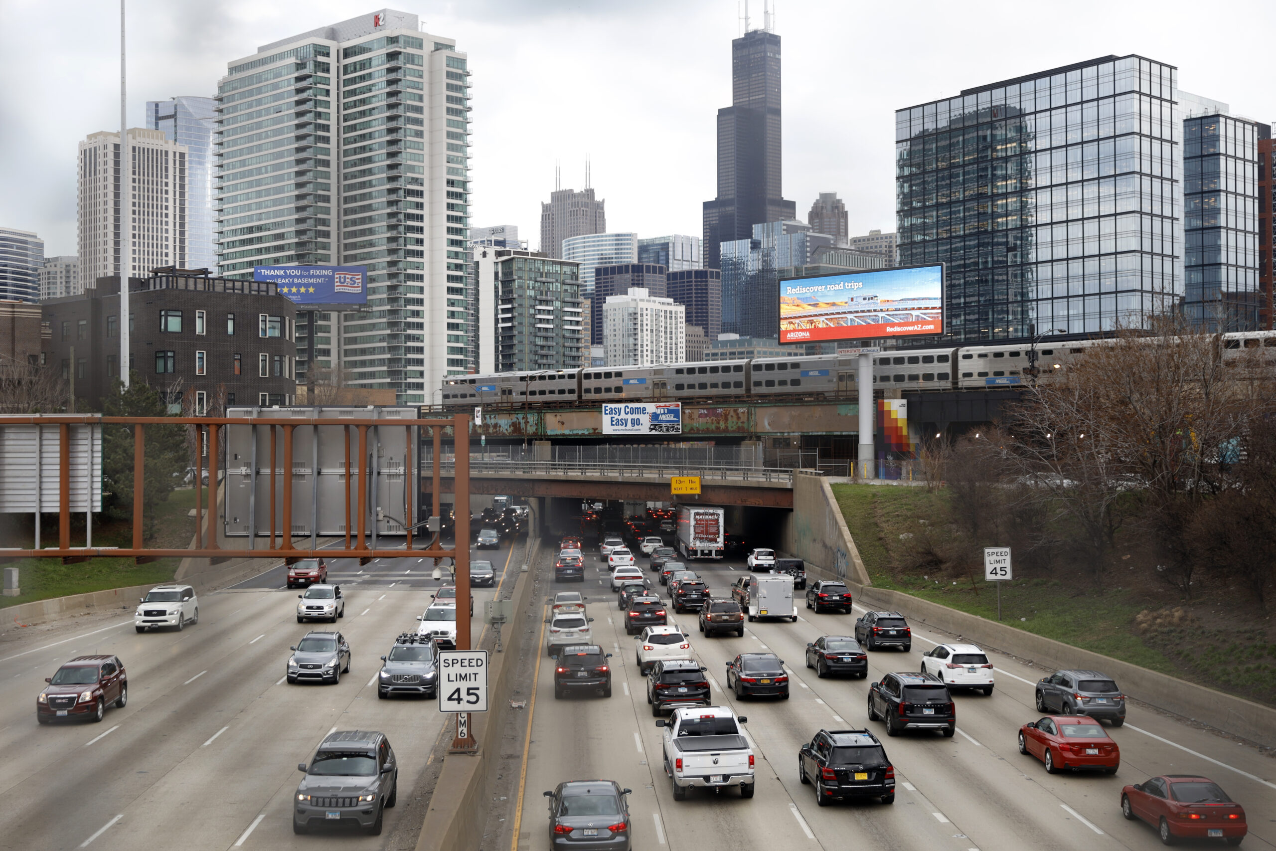 FILE - In this March 31, 2021,photo, traffic flows along Interstate 90 highway as a Metra suburban commuter train moves along an elevated track in Chicago. Congress has created a new requirement for automakers: find a high-tech way to keep drunken people from driving cars. It's one of the mandates along with a burst of new spending aimed at improving auto safety amid escalating road fatalities in the $1 trillion infrastructure package that President Joe Biden is expected to sign soon. (AP Photo/Shafkat Anowar, File)