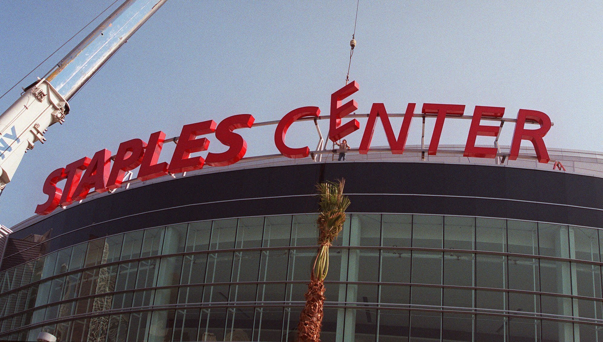 FILE - Construction workers put the finishing touches on the Staples Center sign outside the arena in downtown Los Angeles on Thursday, Sept. 16, 1999. Staples Center is getting a new name. Starting Christmas Day, it will be Crypto.com Arena. The downtown Los Angeles home of the NBA's Lakers and Clippers, the NHL's Kings and the WNBA's Sparks will change its name after 22 years of operation, arena owner AEG announced Tuesday night, Nov. 16, 2021. (AP Photo/Xerro Ryan Covarrubias, File)