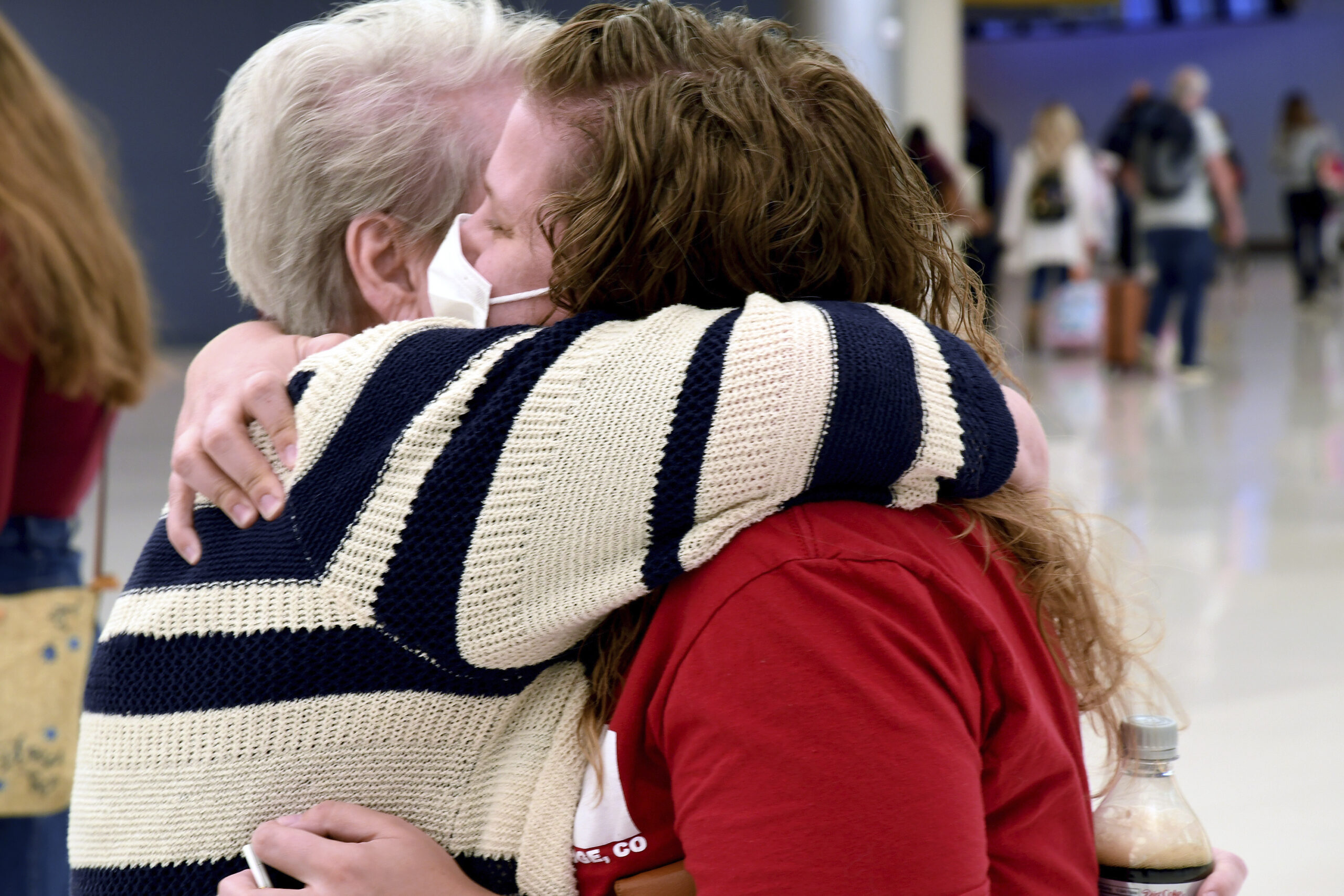 Jocelyn Ragusin hugs her mother, who arrived at Denver International Airport from Rapid City, South Dakota, on Tuesday, Nov. 23, 2021. Ragusin said about seven or eight family members would be gathering for the holiday and that the group had not discussed each other's vaccination status beforehand. Ragusin's husband contracted COVID-19 and spent four days in the intensive care unit in October 2020, but the family is willing to accept a certain level of risk to have a sense of community back. (AP Photo/Thomas Peipert)