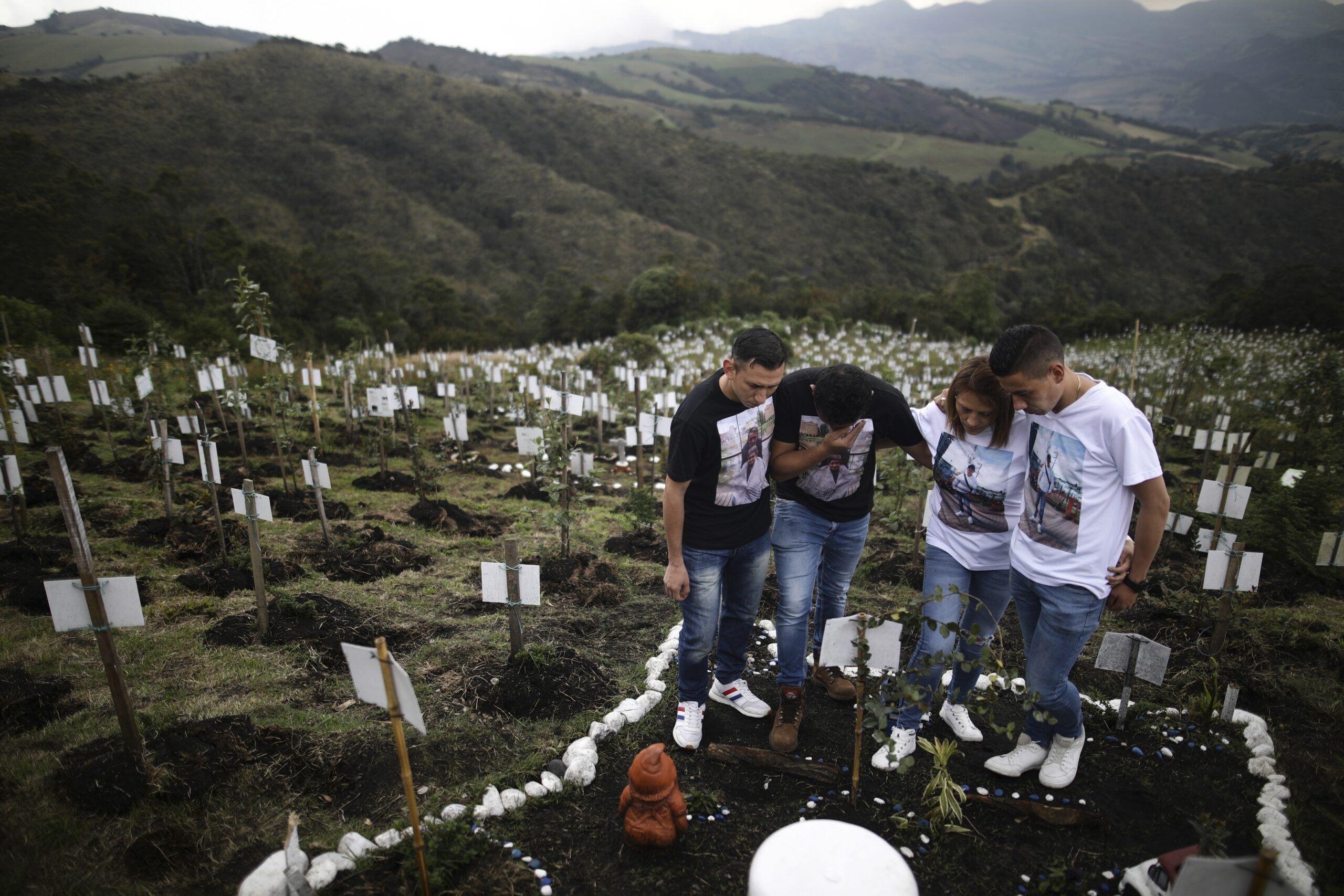 Relatives of Luis Enrique Rodriguez, who died of COVID-19, visit where he was buried on a hill at the El Pajonal de Cogua Natural Reserve, in Cogua, north of Bogota, Colombia, Monday, Oct. 25, 2021. Rodriguez died May 14, 2021. Relatives bury the ashes of their loved ones who died of coronavirus and plant a tree in their memory. (AP Photo/Ivan Valencia)
