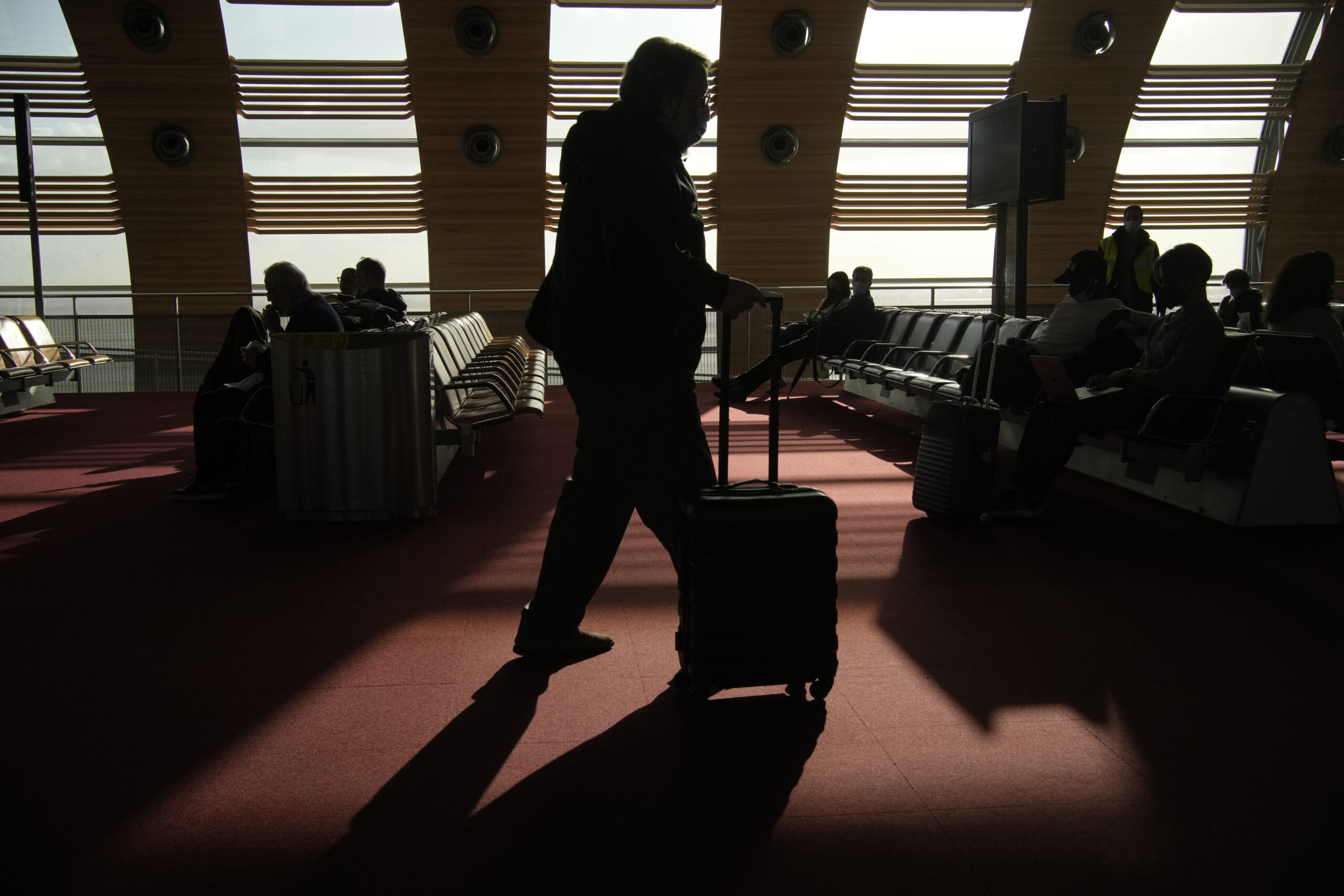 A passenger for United States wheels his luggage in the waiting zone before boarding a flight in the Charles de Gaulle airport, north of Paris, Monday, Nov.8, 2021. The U.S. lifted restrictions Monday on travel from a long list of countries including Mexico, Canada and most of Europe, allowing tourists to make long-delayed trips and family members to reconnect with loved ones after more than a year and a half apart because of the pandemic. (AP Photo/Christophe Ena)