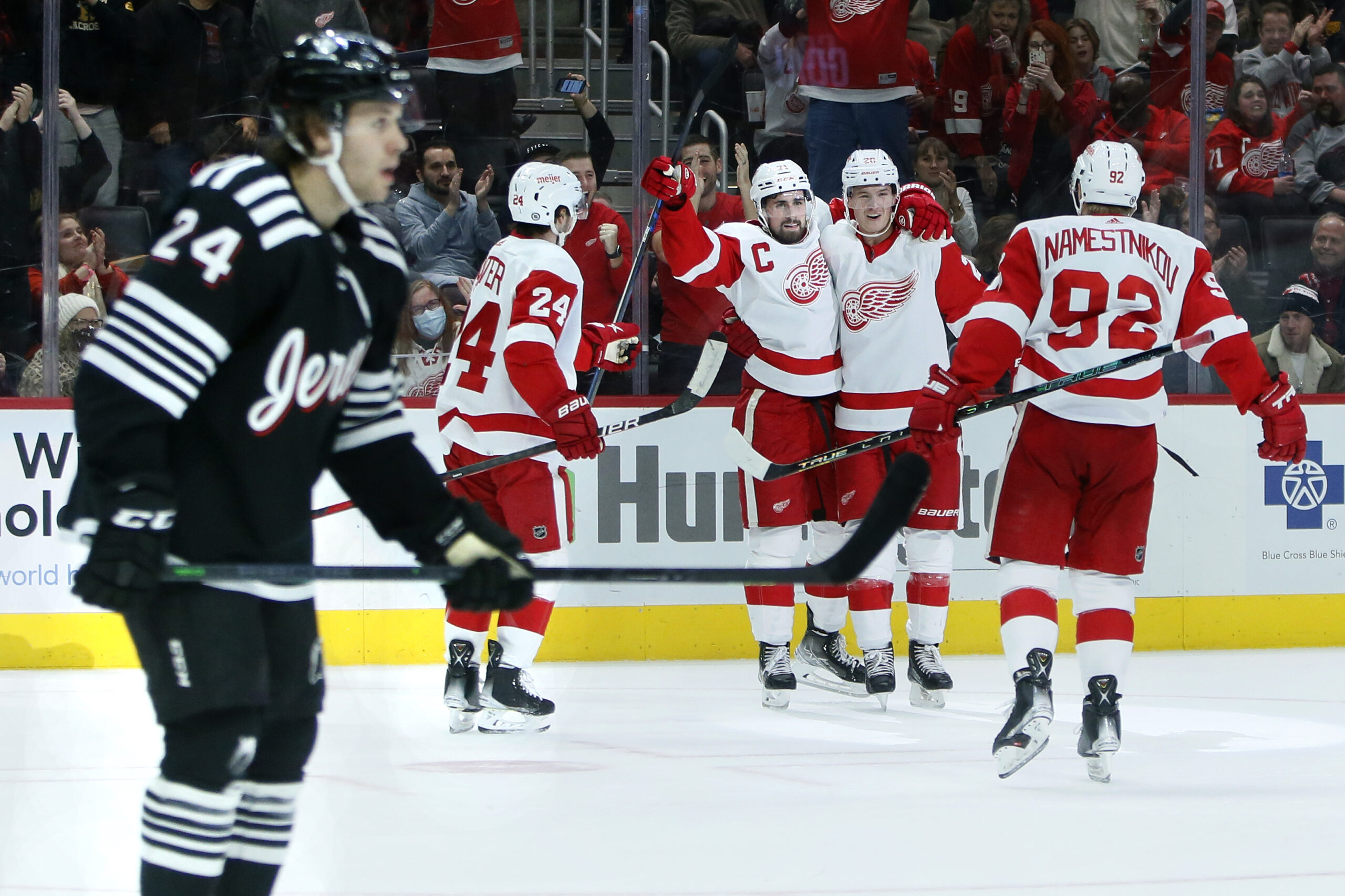 Detroit Red Wings center Dylan Larkin, third from left, celebrates his second goal of the game with center Pius Suter (24), defenseman Gustav Lindstrom and center Vladislav Namestnikov (92) as New Jersey Devils defenseman Ty Smith (24) skates off during the second period of an NHL hockey game Saturday, Dec. 18, 2021, in Detroit. (AP Photo/Duane Burleson)