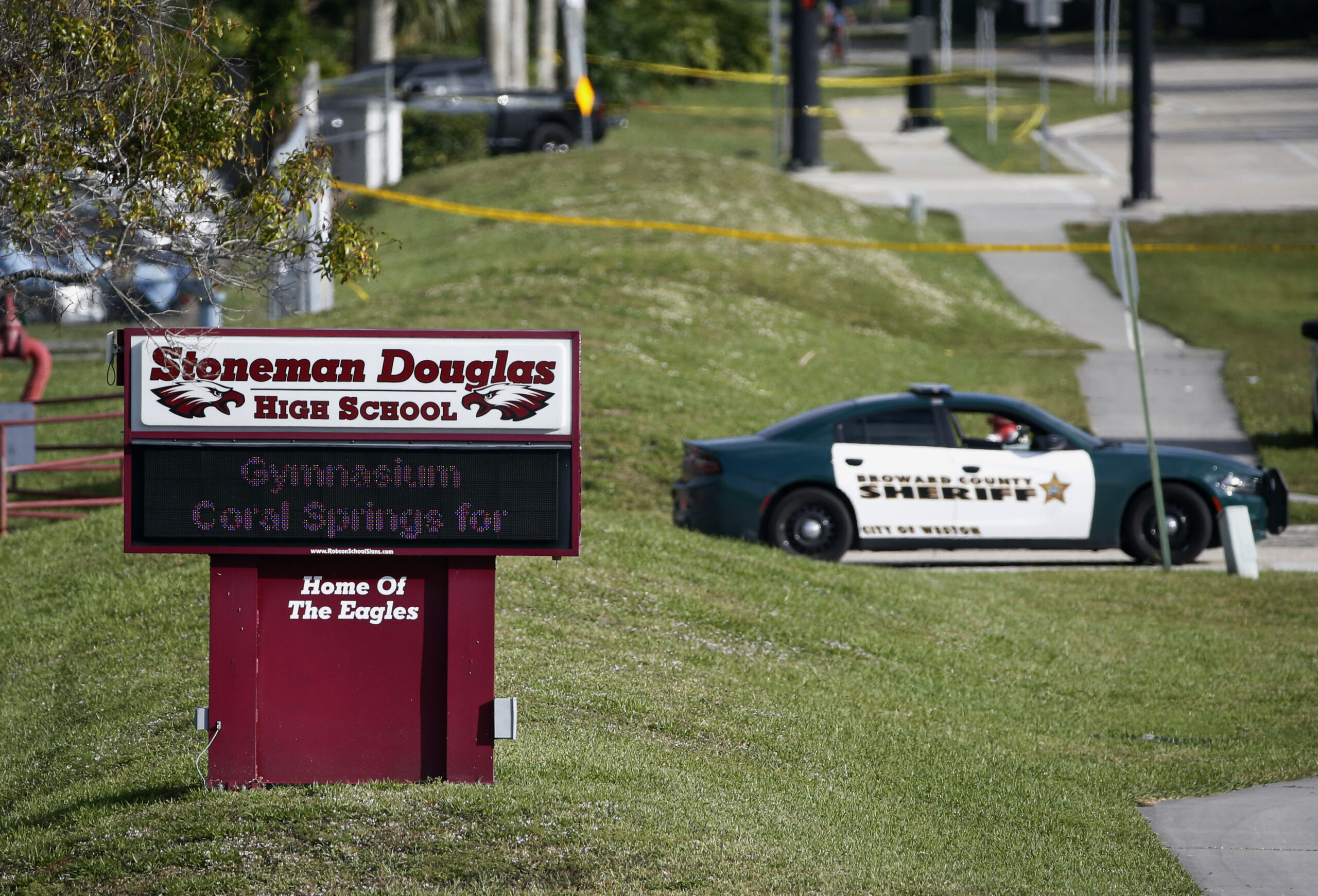 FILE- Law enforcement officers block off the entrance to Marjory Stoneman Douglas High School Feb. 15, 2018 in Parkland, Fla., following a deadly shooting at the school. The families of most of those killed in the 2018 Florida high school massacre have settled their lawsuit against the federal government. Sixteen of the 17 killed at Marjory Stoneman Douglas High in Parkland had sued over the FBI’s failure to stop the gunman even though it had received information he intended to attack. The settlement reached Monday, Nov. 22, 2021 is confidential. (AP Photo/Wilfredo Lee, File)
