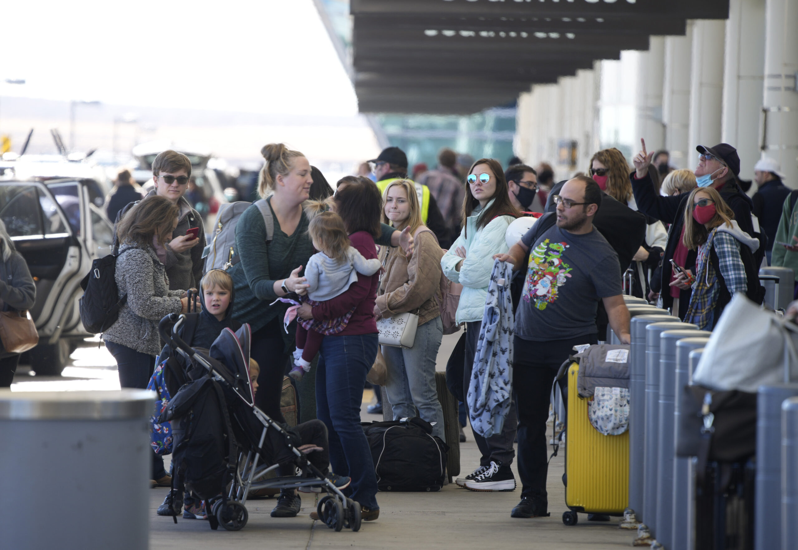 Travelers queue up at the Southwest Airlines curbside check-in area at Denver International Airport Sunday, Dec. 26, 2021, in Denver. Airlines canceled hundreds of flights Sunday, citing staffing problems tied to COVID-19 to extend the nation's travel problems beyond Christmas. (AP Photo/David Zalubowski)