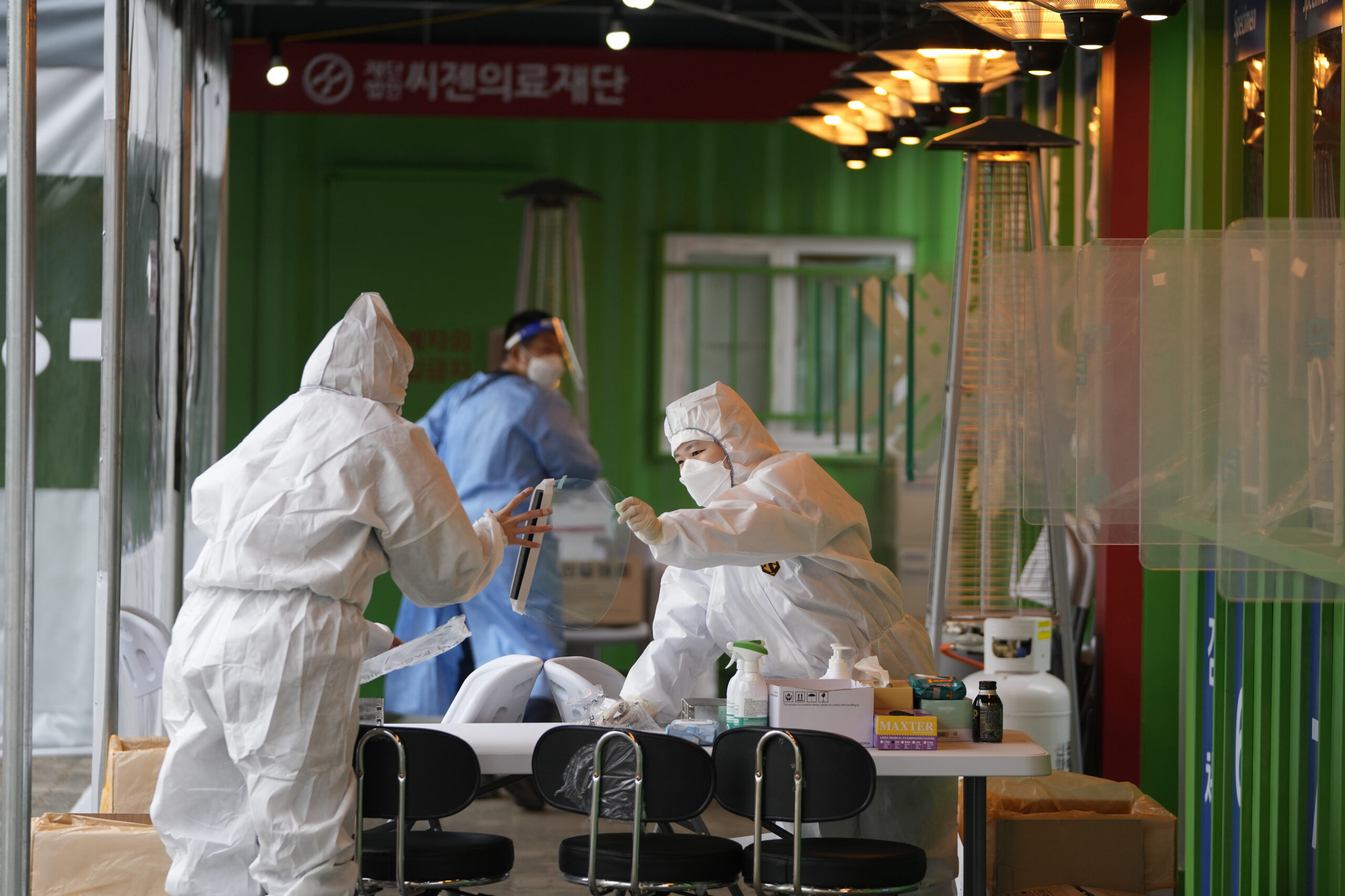 Medical workers wearing protective gear prepare to take samples at a temporary screening clinic for the coronavirus in Seoul, South Korea, Wednesday, Dec. 29, 2021. (AP Photo/Lee Jin-man)